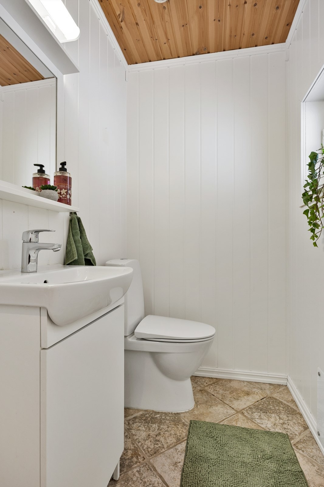 Lyst, enkelt og praktisk toalettrom med toalett og servant i servantskap. Galleribilde