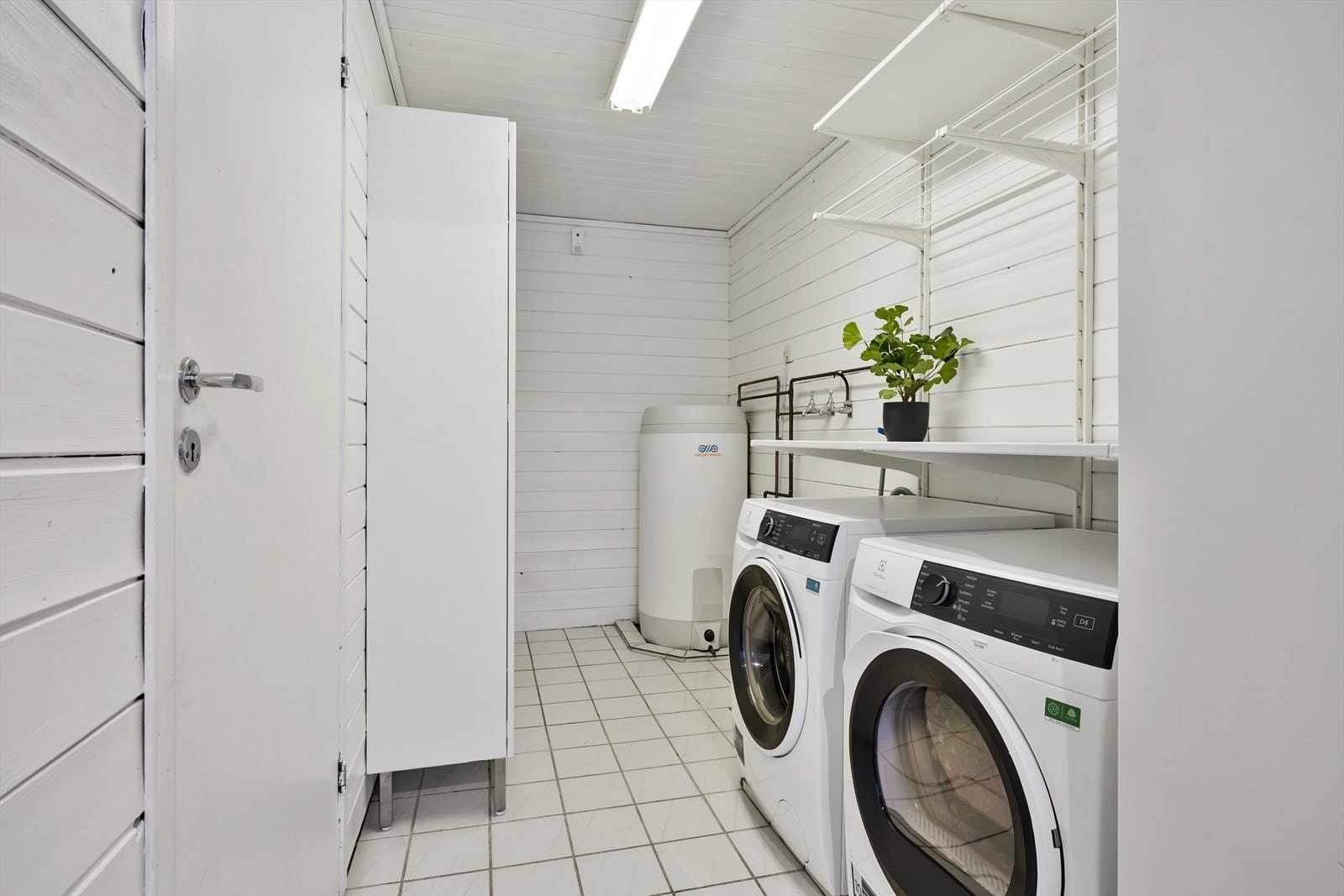 Stort og praktisk vaskerom med flislagt gulv og rom for oppbevaring. Galleribilde