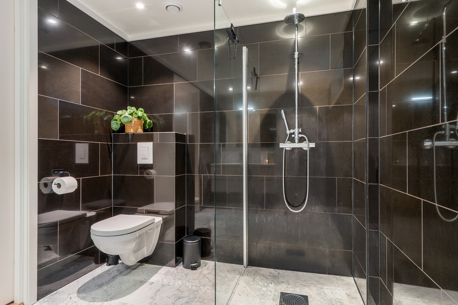 Badet er innredet med vegghengt toalett, baderomsinnredning med heldekkende servant samt dusjhjørne med dusjvegger Galleribilde