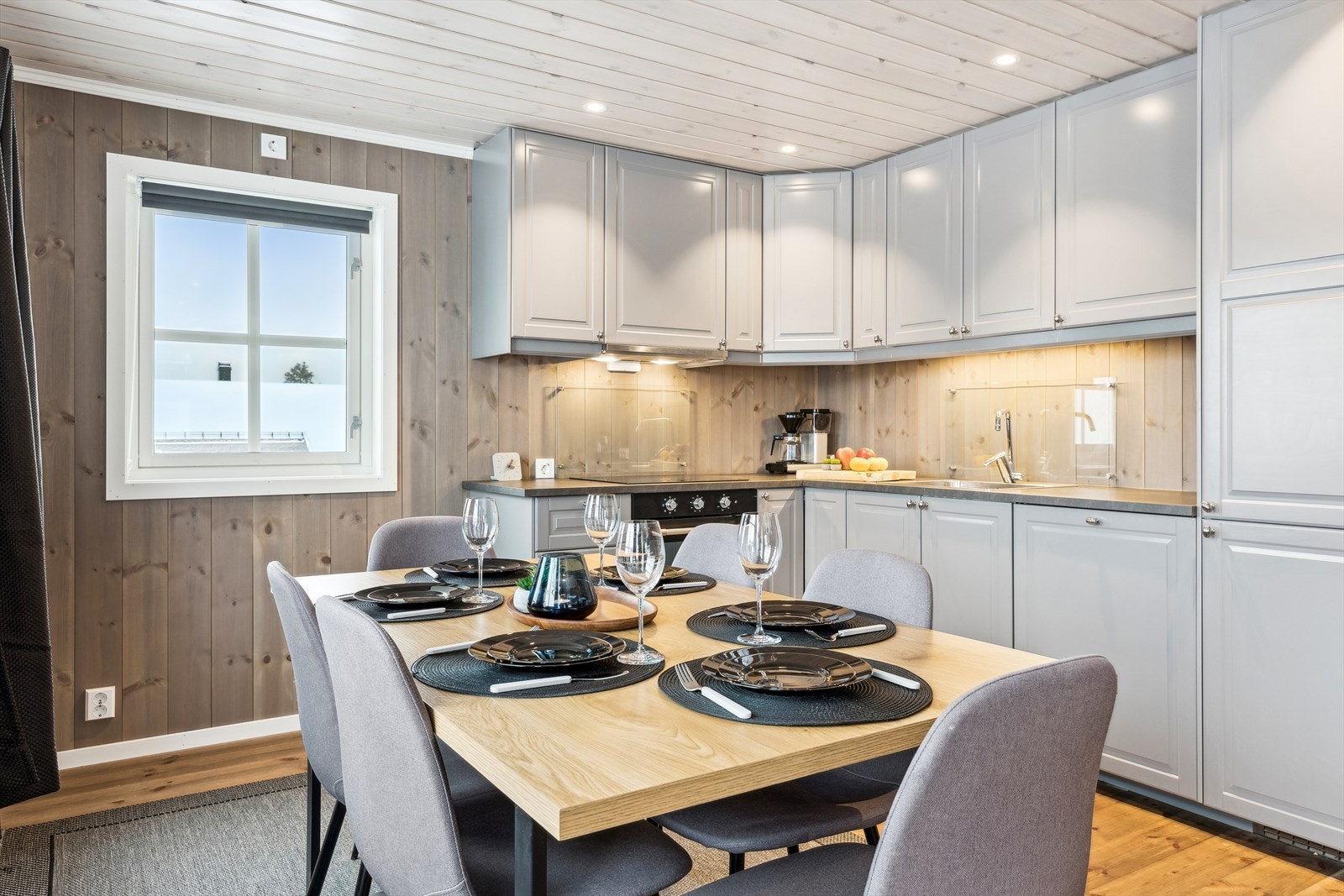 Et koselig kjøkken med takhøye skap og integrerte hvitevarer. Galleribilde