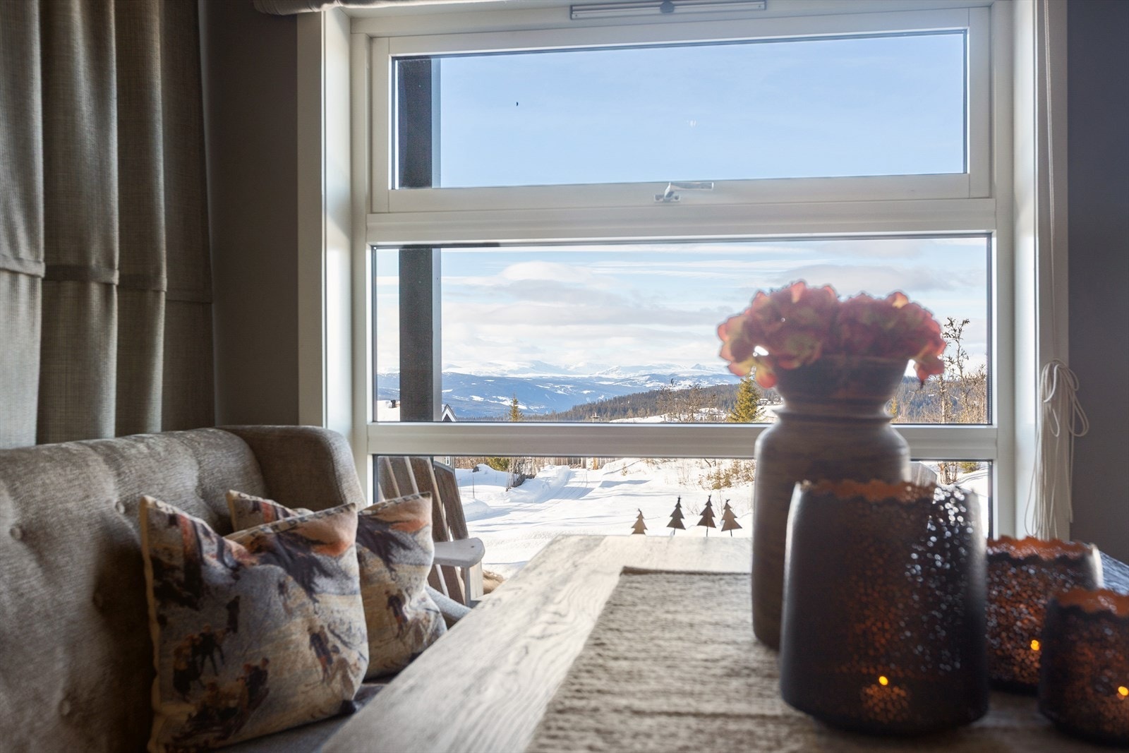 Her er det delikate farge- og materialvalg, og store vinduene, sammen med terrassedør med glass felt, gjør det enkelt å nyte den flotte utsikten fra stue og kjøkken. Galleribilde