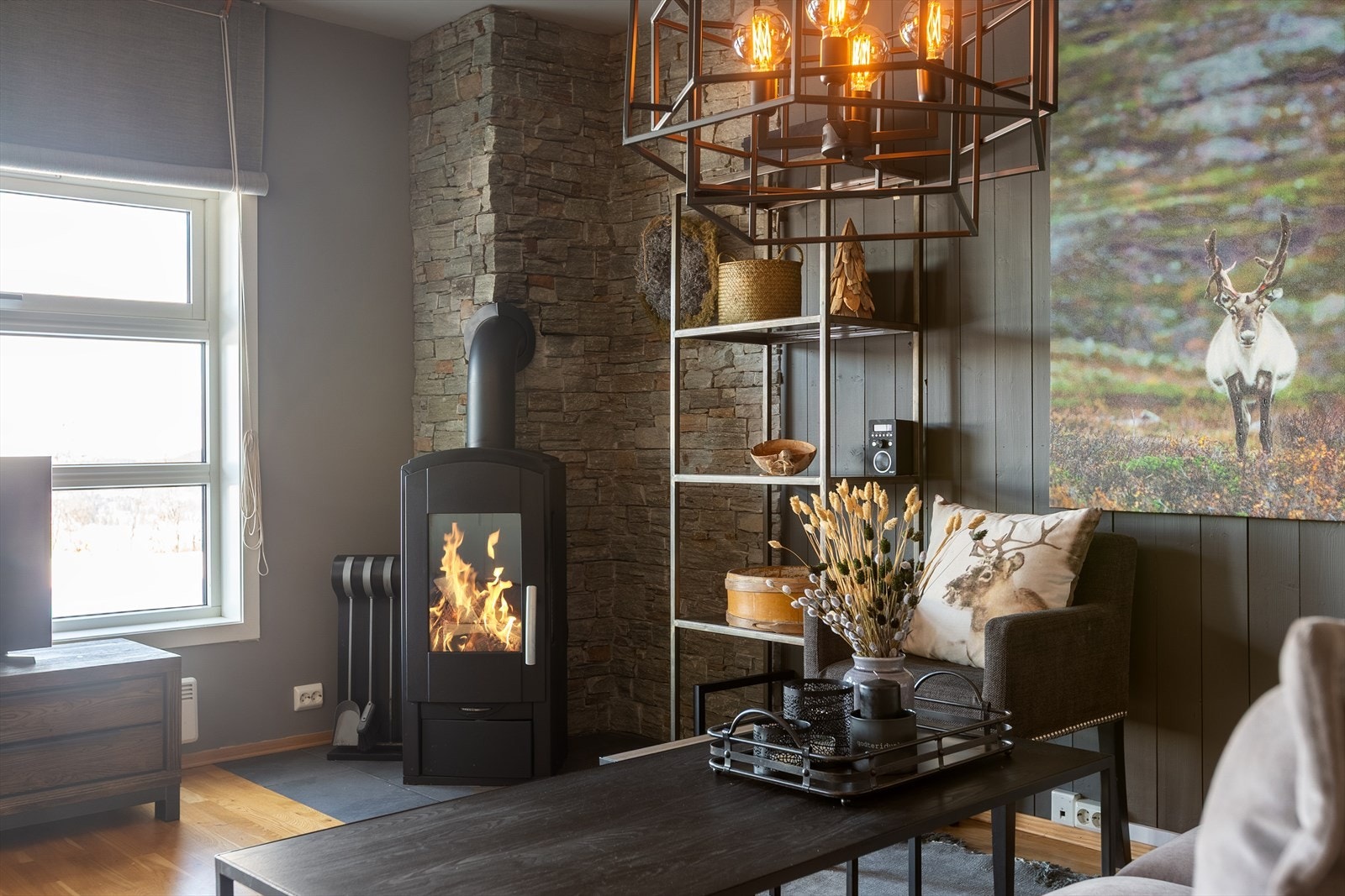 Det er fin plass til både spisegruppe og sofa, og en stilig peisovn med innsyn sørger for lun og god varme. Galleribilde