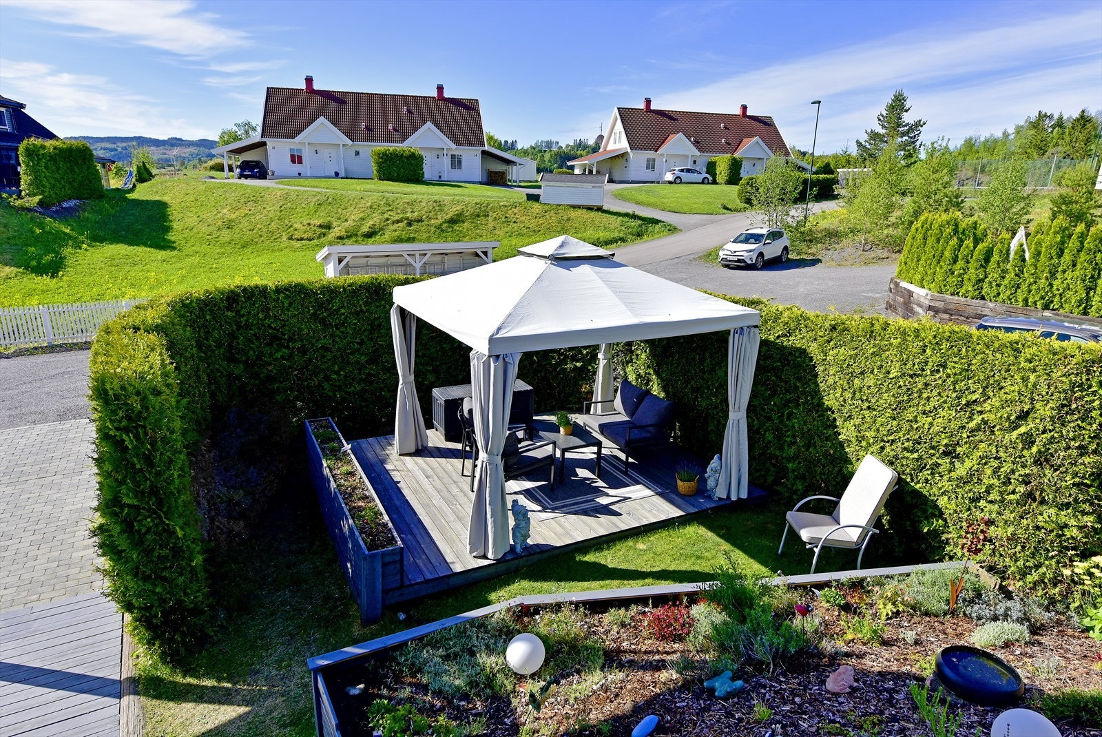 Tomten er opparbeidet med plen, beplantning og forstøtningsmurer. Gårdsplass belagt med belegningsstein Galleribilde