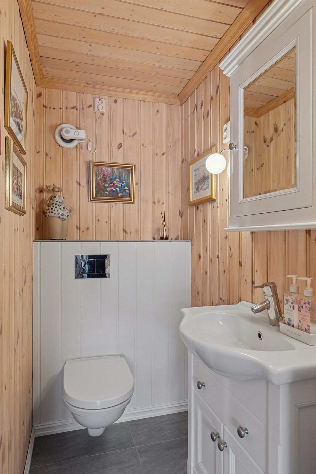 Det er separat toalettrom med vegghengt toalett og enkel innredning. Fliser på gulv, panel på vegger og himling. Galleribilde