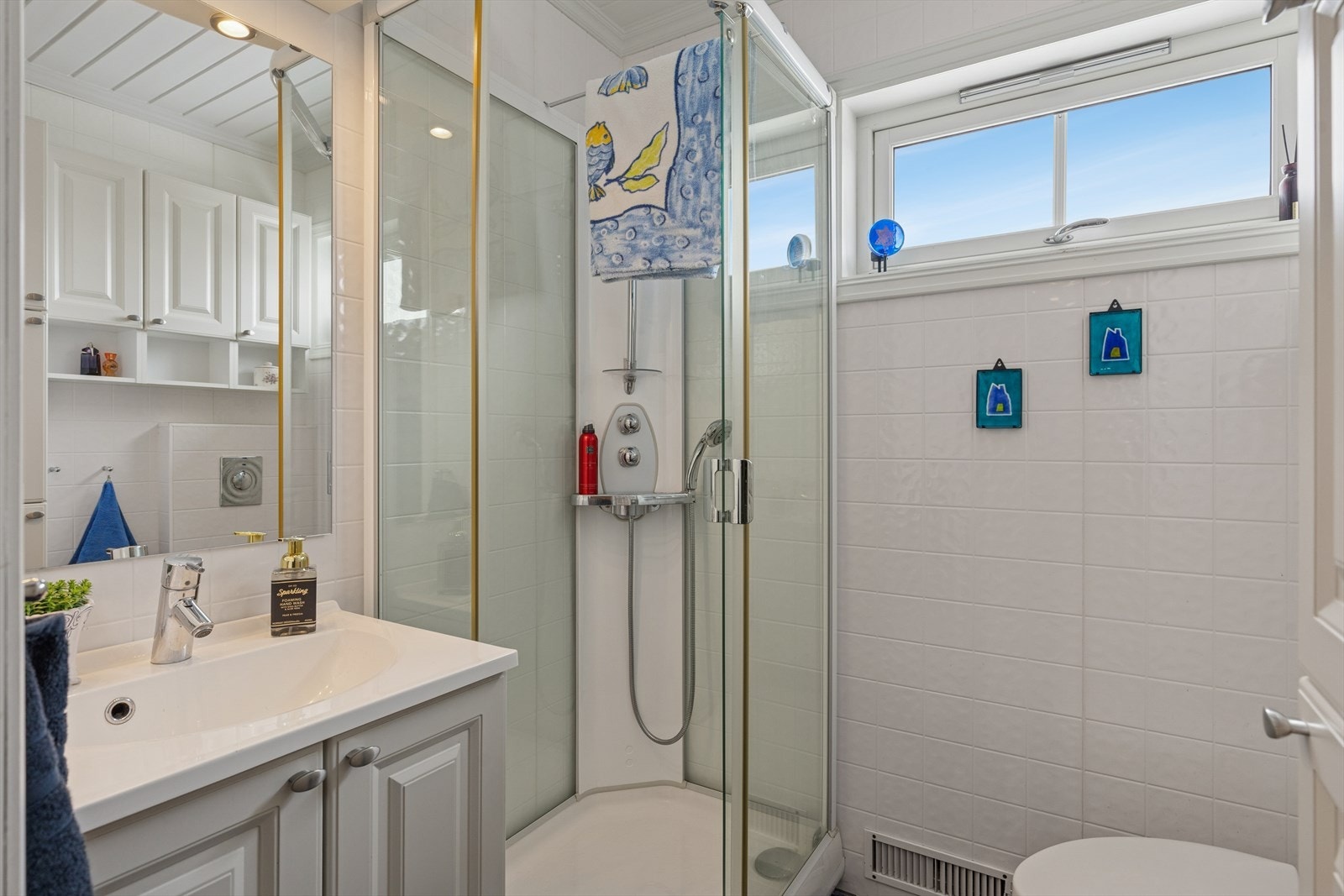 Baderom utstyrt med servant nedfelt i skapinnredning, dusjkabinett og wc. Galleribilde