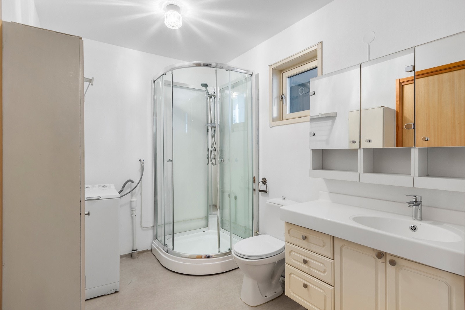 Romslig bad med dusjkabinett, servant i innredning og speilskap med oppbevaring Galleribilde