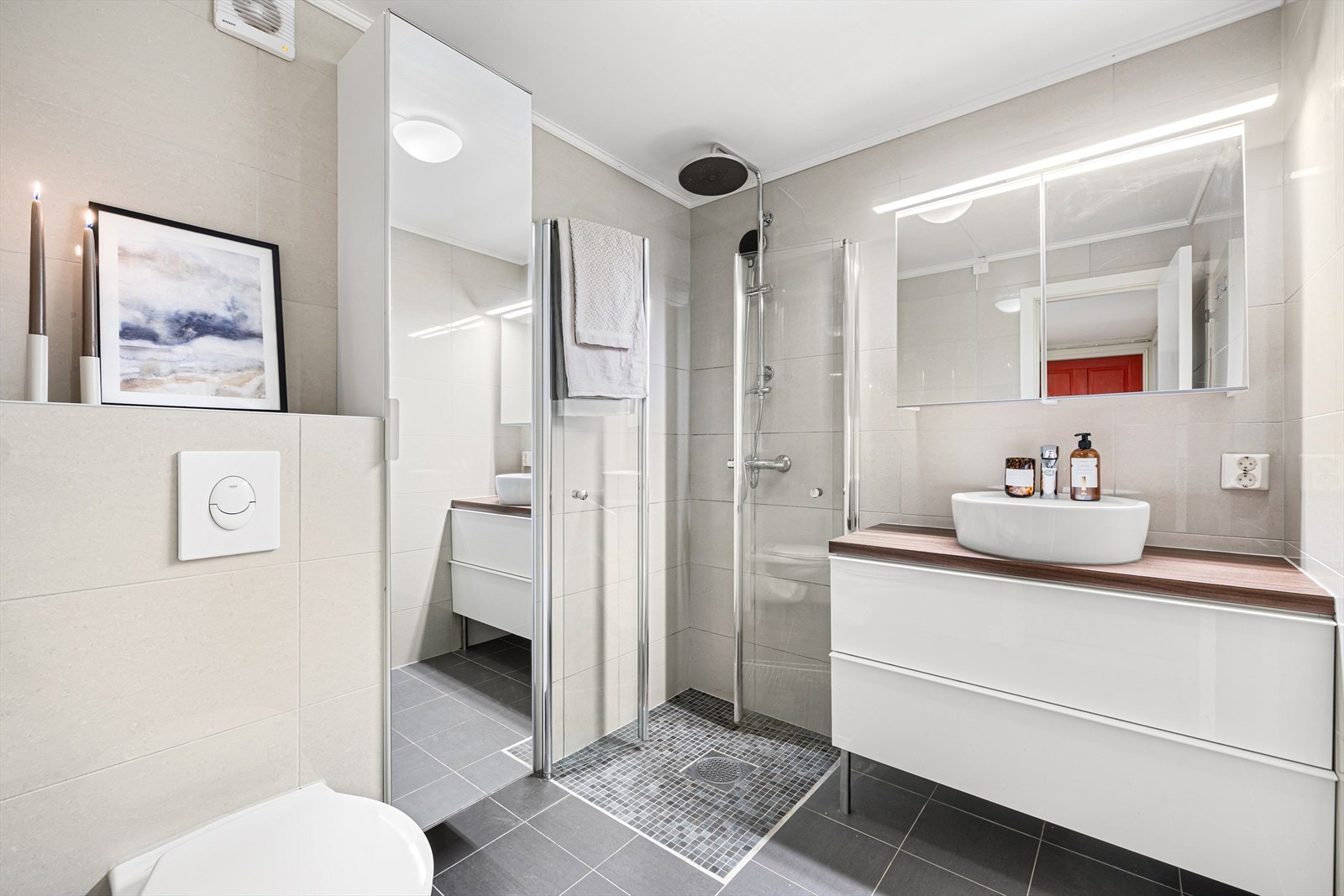 Pent flislagt bad fra 2016. Innredet med servantskap og speil, praktisk dushjørne med innfellbare dører og WC. Galleribilde