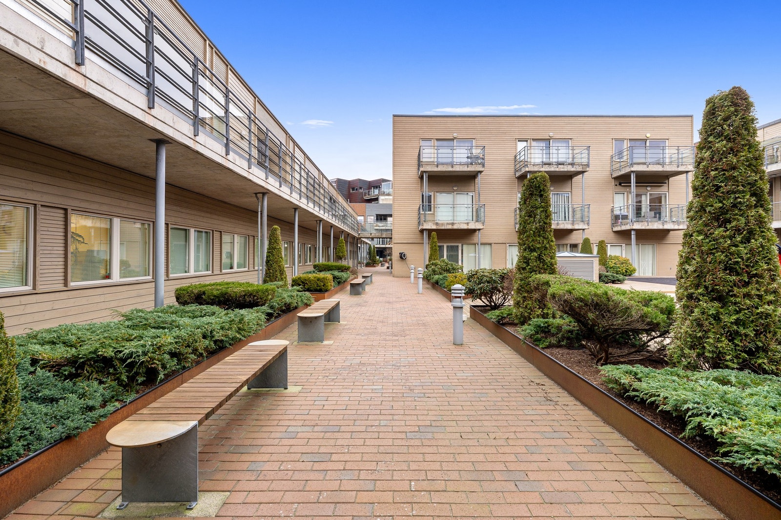 Utenfor egen inngangsdør har man i tillegg direkte adkomst til et velholdt felles atrium. Her er det steinsatte gangstier med utebelysning kombinert med pent beplantede bed. Galleribilde