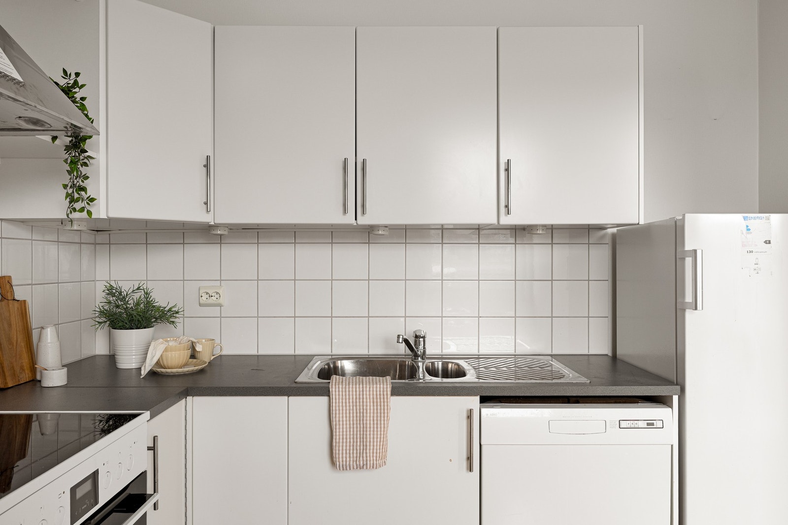 Innredningen har slette fronter i hvit utførelse, kombinert med mørk laminert benkeplate. Galleribilde