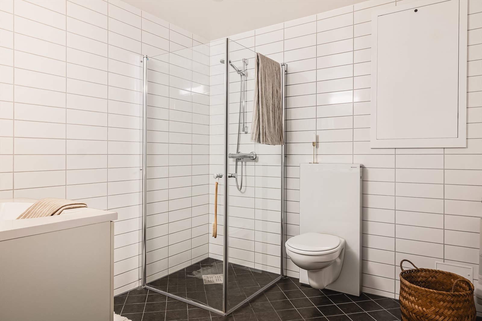 Pent og funksjonelt bad med et areal på 5,5 kvm. Badet er utført med keramiske fliser på gulv og vegger, og malt platekledning i himling med integrerte LED-spotlights som gir behagelig belysning. Galleribilde