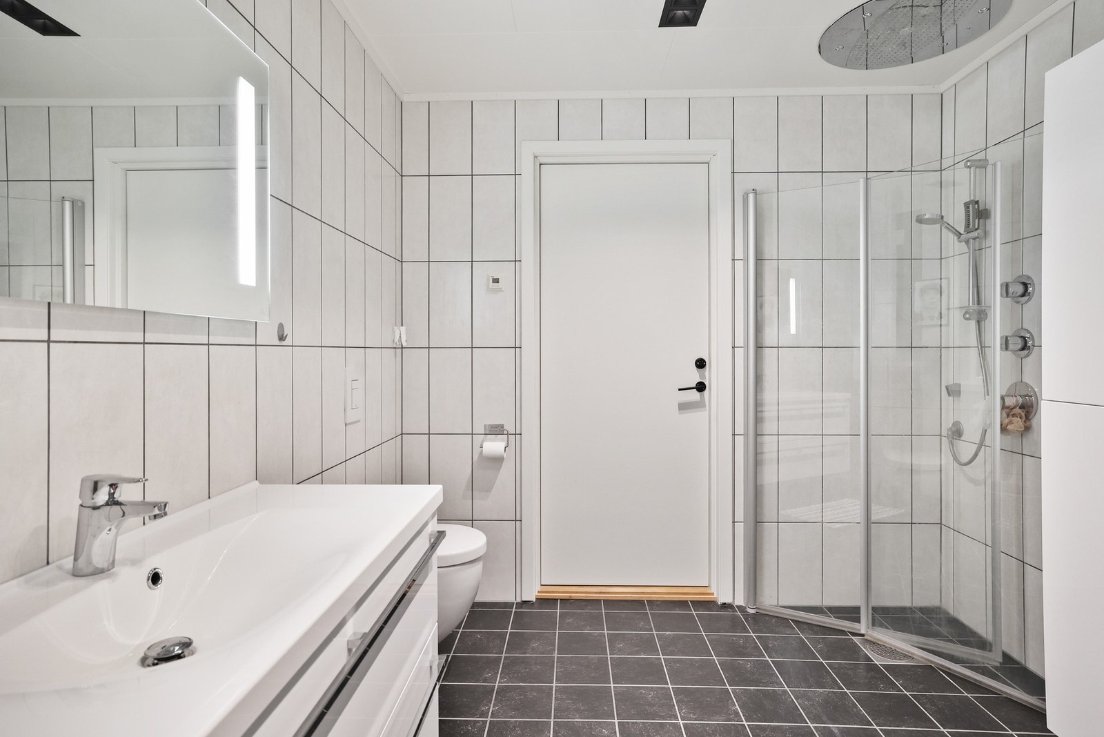 Badet har flislagt gulv med gulvvarme og vegghengt servantinnredning. Galleribilde