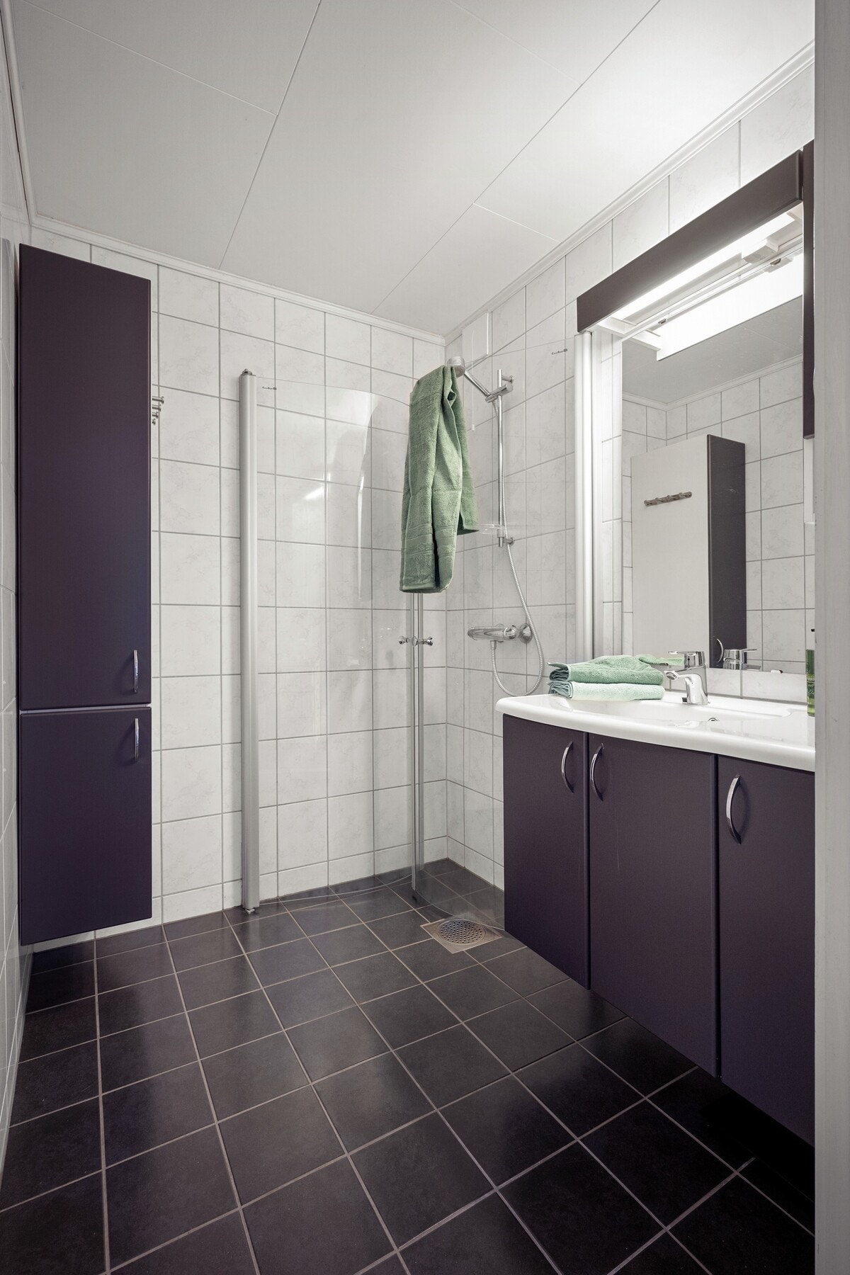 Pent og funksjonelt baderom med flislagte overflater og gulvvarme. Galleribilde