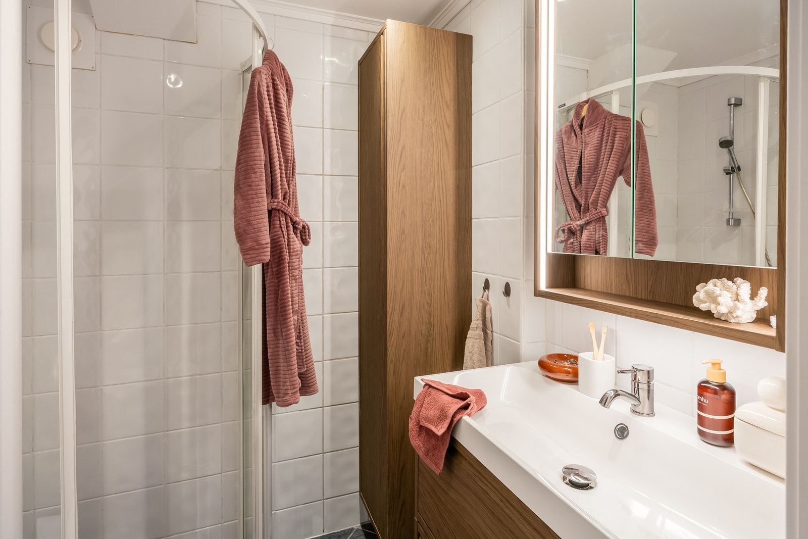 Badet er utstyrt med vegghengt toalett, dusjhjørne med innfellbare dører og sevant med over- og underskap. Galleribilde