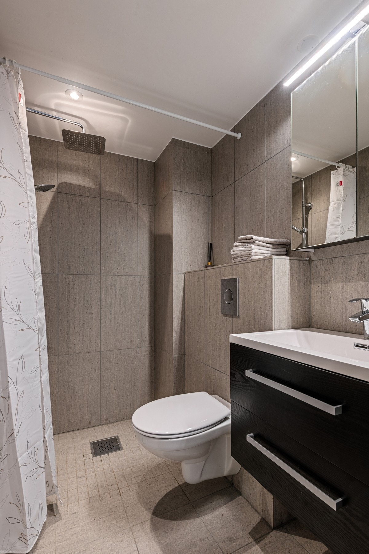 Lekkert bad som er flislagt på gulv og vegger Galleribilde