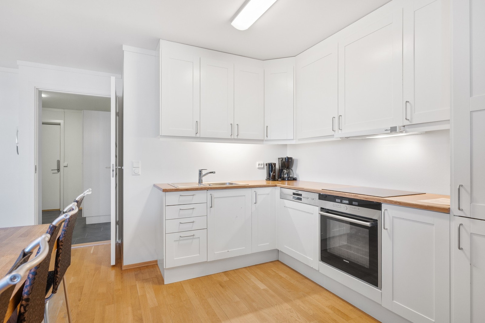 Kjøkkenet har flott innredning med rammefronter og benkeplate i laminat med nedfelt vaskebeslag. Videre er kjøkkenet utstyrt med integrerte hvitevarer som platetopp, stekeovn, kjøl-/frys og oppvaskmaskin fra Siemens. Over kokesonen er det integrert ventil Galleribilde