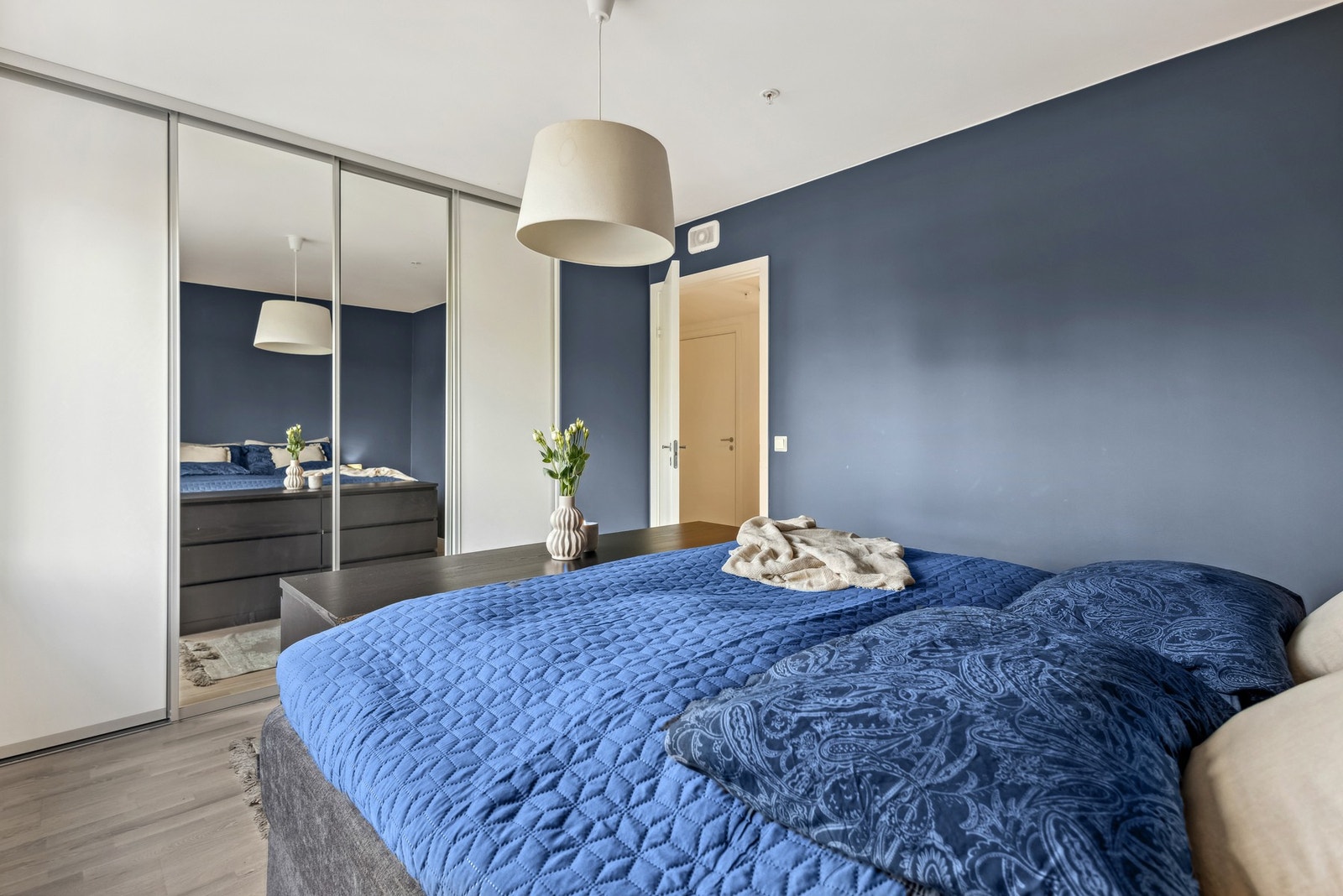 Her er soverommet innredet med skyvedørsgarderobe med speil, som gir god plass til klesoppbevaring. Det lune fargevalget gir rommet et harmonisk og innbydende preg. Galleribilde