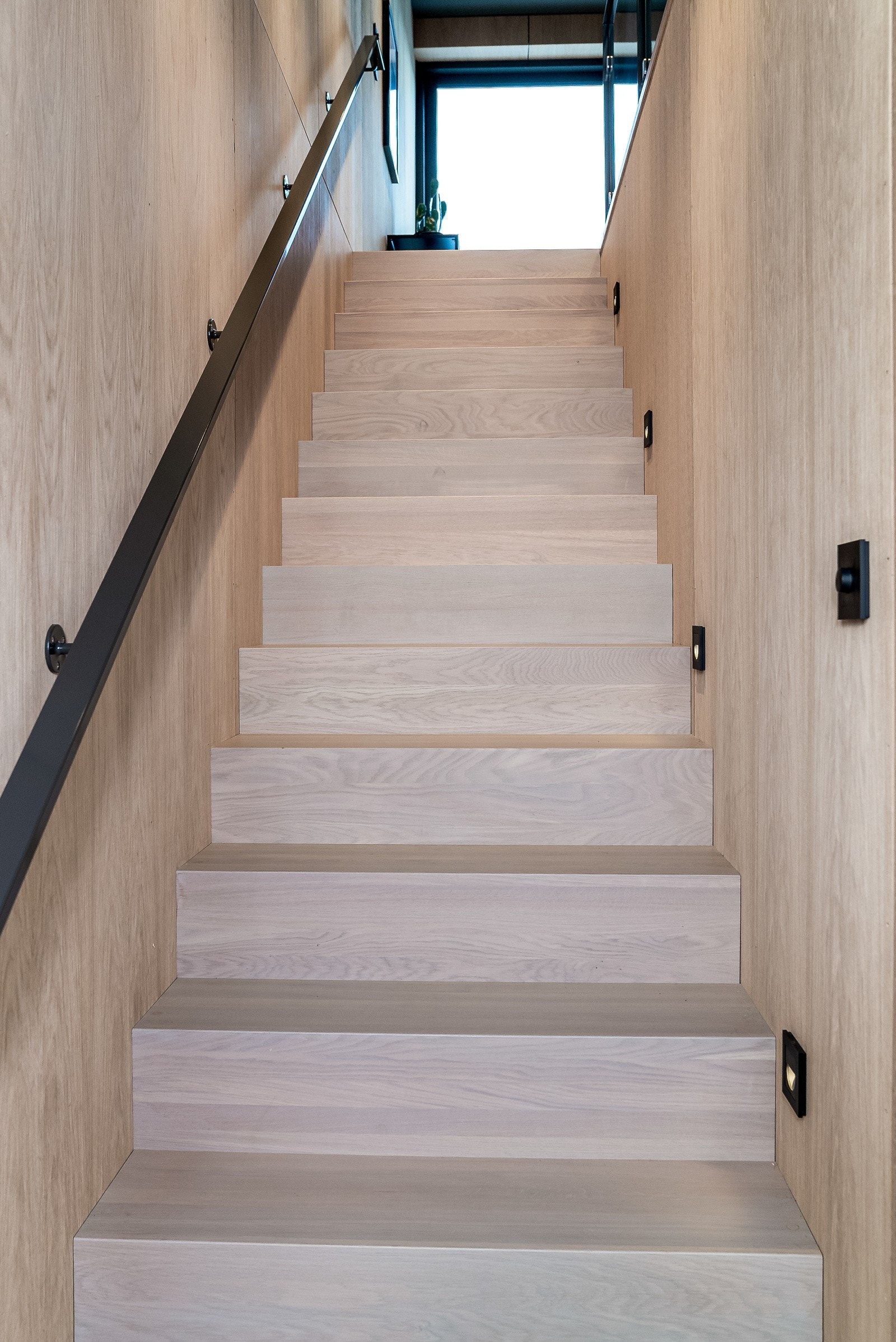 Fra gangen nede er det en flott eiketrapp opp til 2. etasje med lys langs trinnene Galleribilde