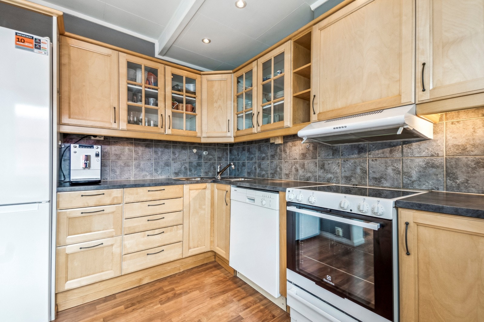 Kjøkkenet i leiligheten er praktisk utformet i en L-form for effektiv bruk av plassen, og har rikelig med oppbevaringsplass i skuffer og skap. Galleribilde