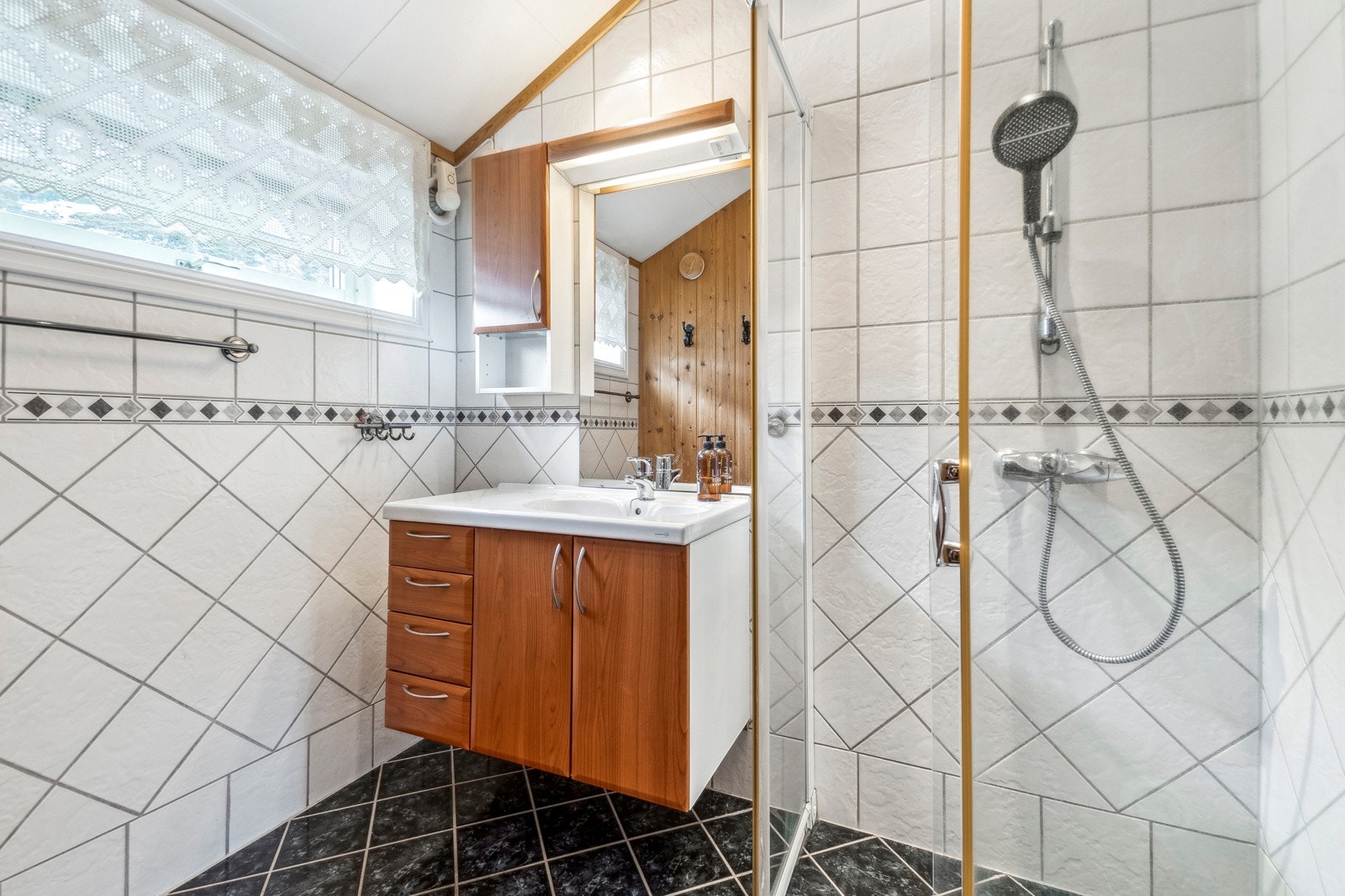 Badet i leiligheten er flislagt både på gulv og vegger, noe som gir et helhetlig og lettstelt uttrykk. Galleribilde