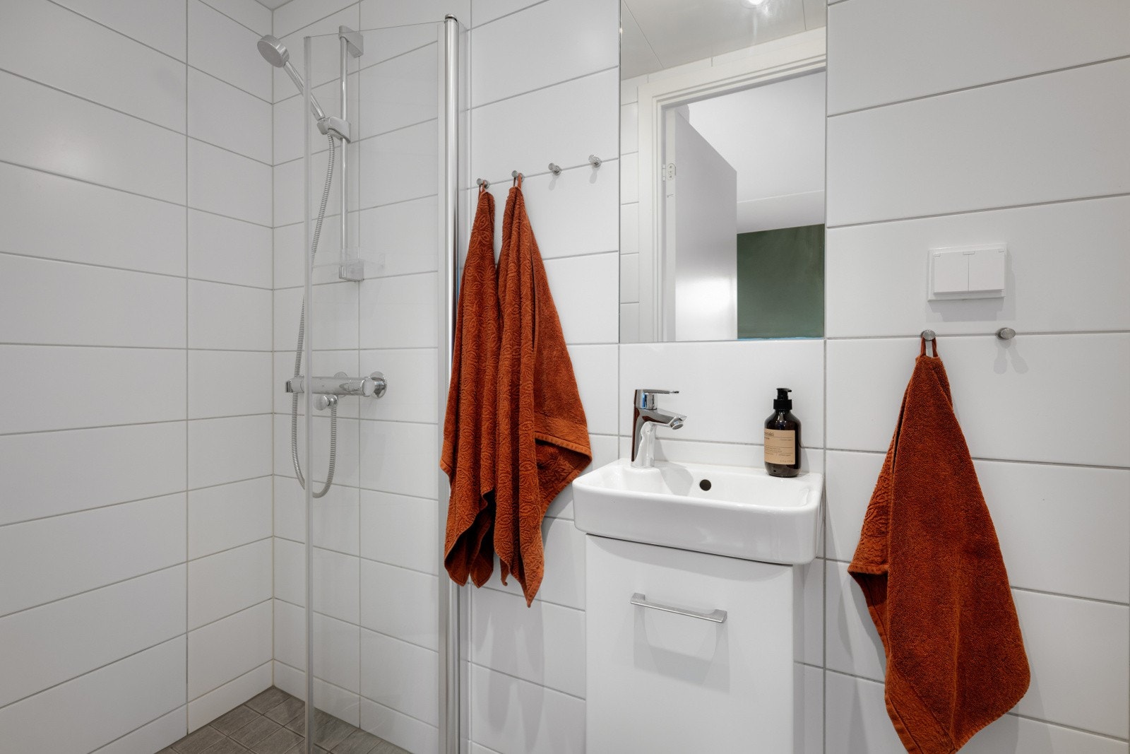 Videre er det veggmontert toalett, nedsenket dusjhjørne med rette svingdører, sluk og termostatstyrt blandebatteri. Galleribilde