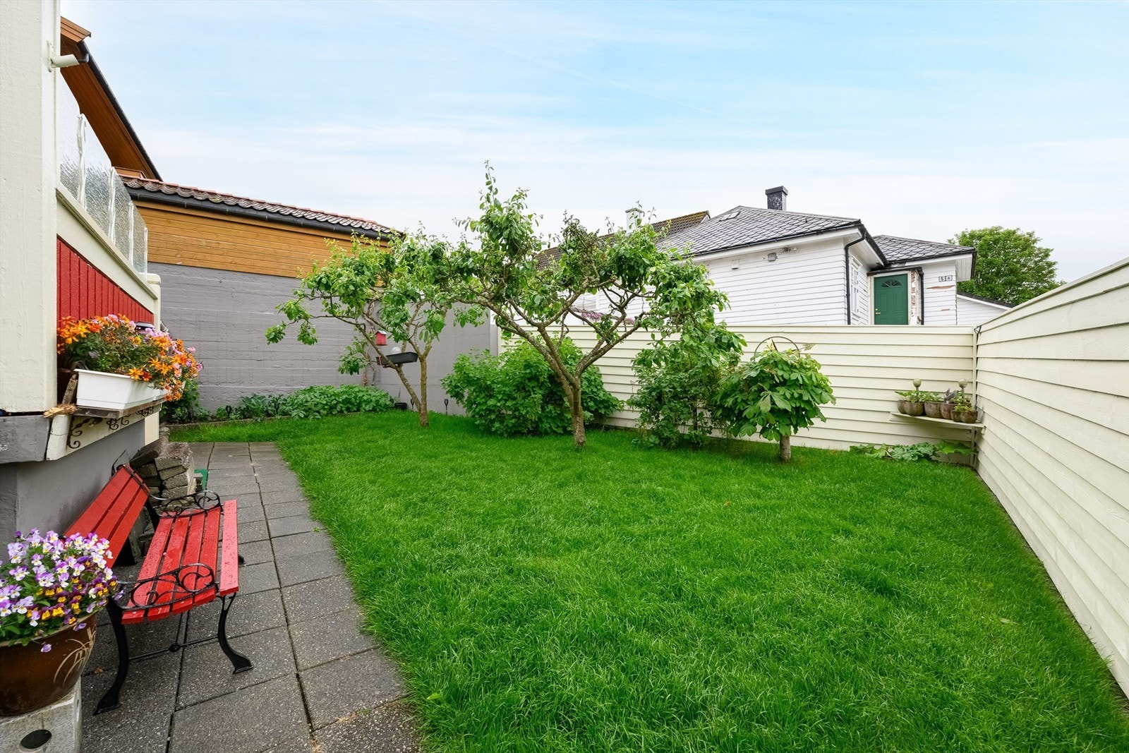 Tomt opparbeidet med belegningsstein, steinheller, diverse beplantninger, plenareal. Galleribilde