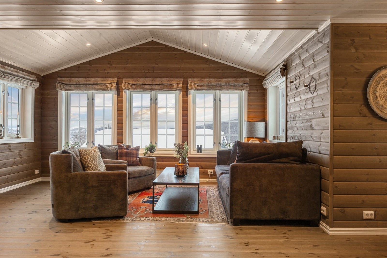 Koselig stue med heltre gulv og beiset panel på veggene. Galleribilde