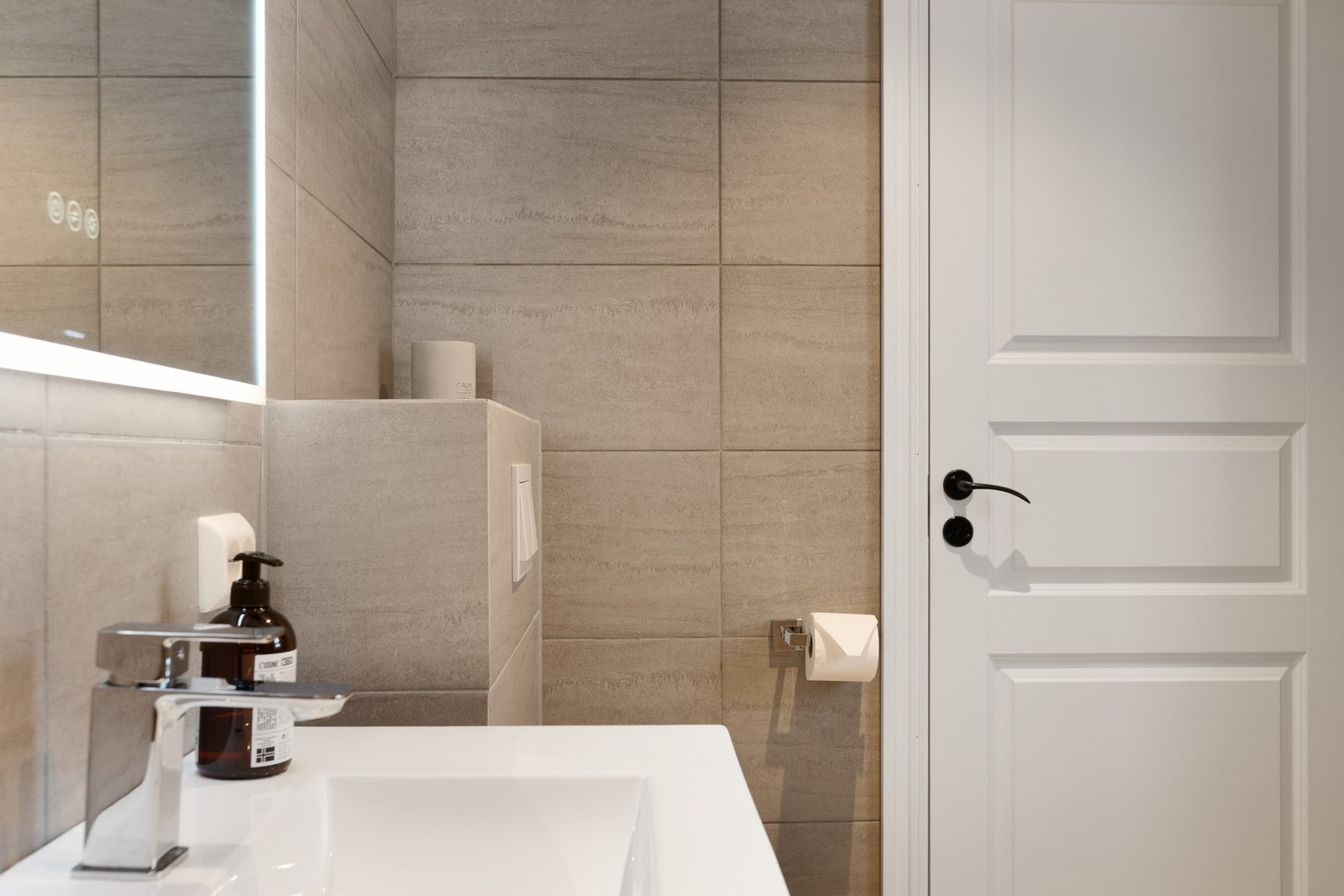 Bad med baderomsinnredning, vegghengt toalett og dusj med glassdører. Galleribilde