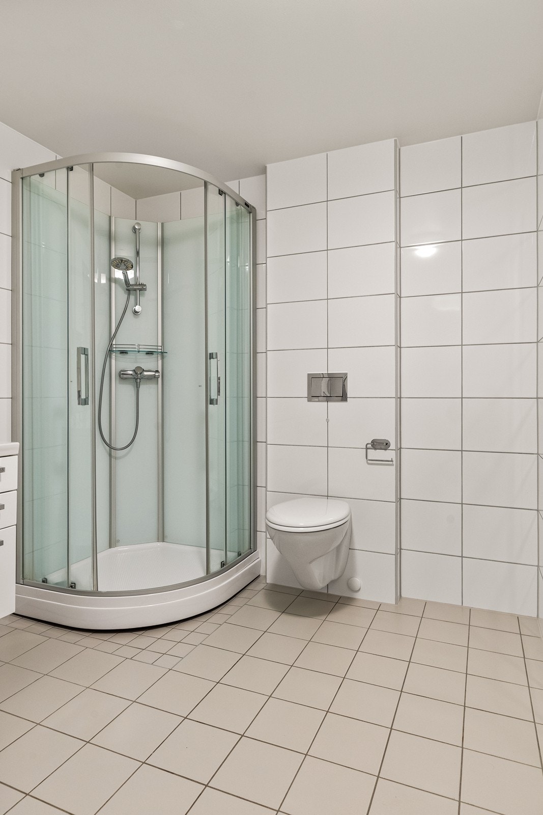 Videre har badet vegghengt toalett og dusjkabinett - en praktisk løsning som utnytter plassen godt. Galleribilde