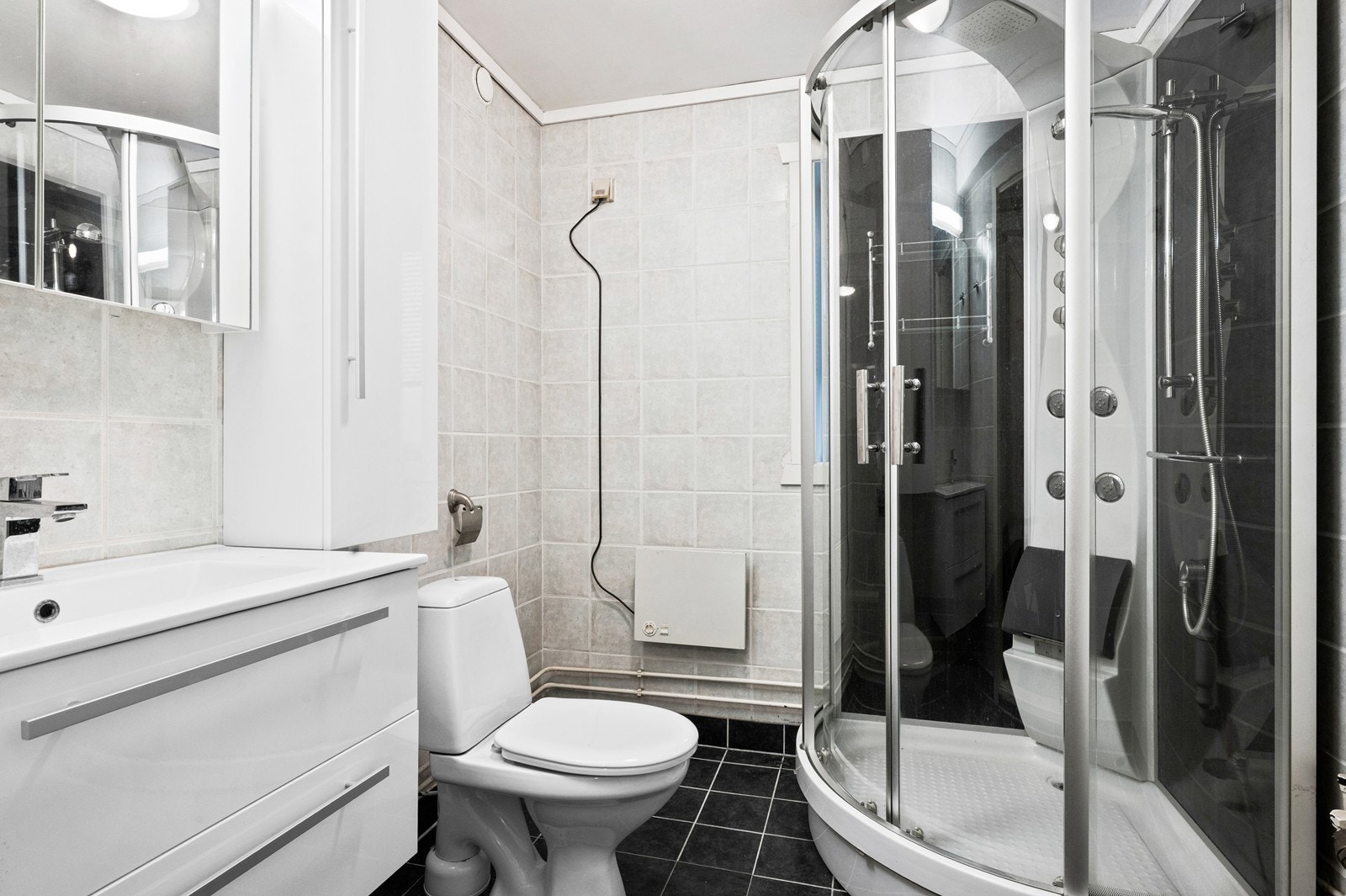 Flislagt bad, av av eldre dato, hvor det er må påregnes oppgradering. Utstyrt med dusjkabinett, servant i innredning med skuffer for lagring, samt speilskap og overskap for ekstra lagringsplass. Videre er det klosett og opplegg for vaskemaskin. Galleribilde