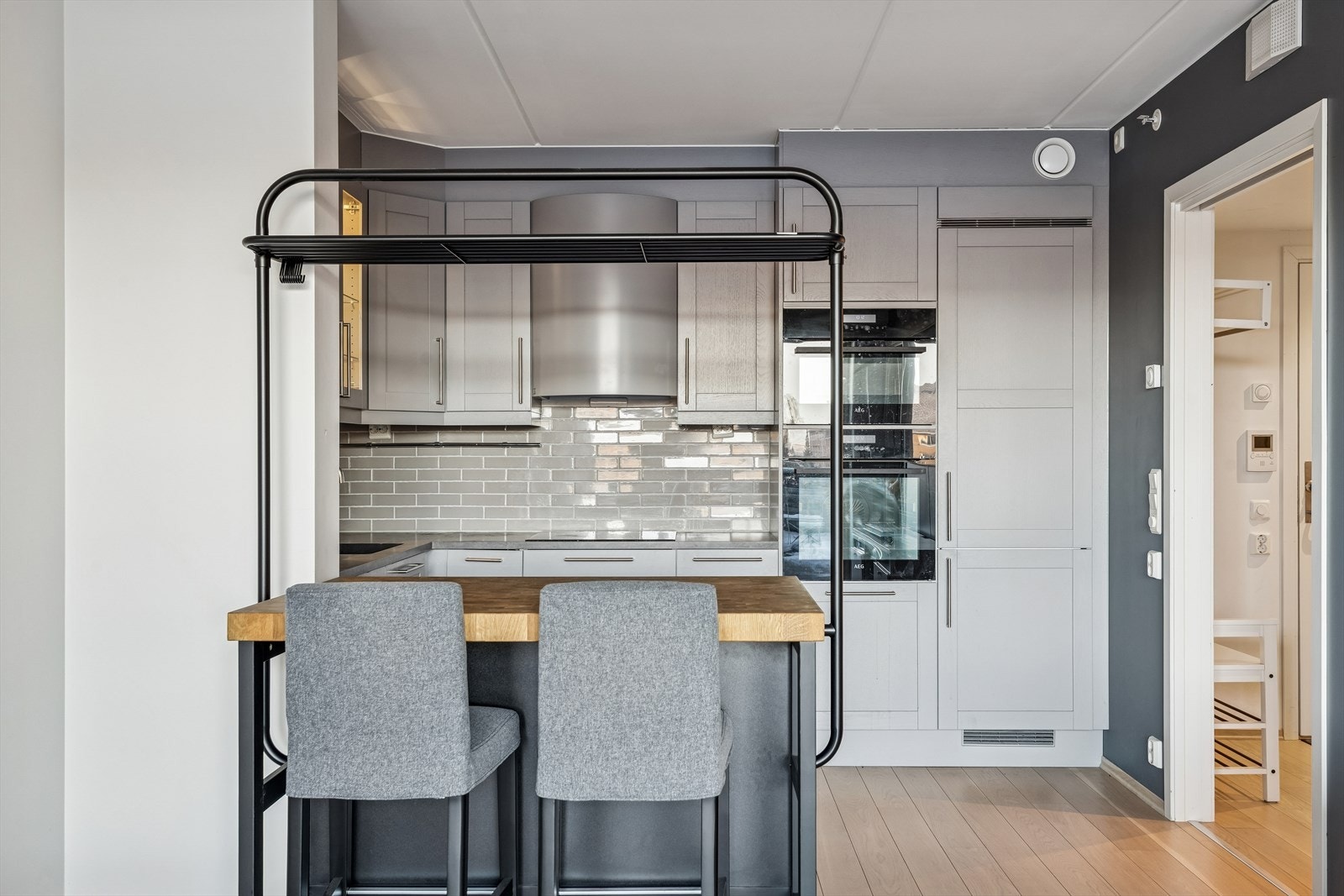 Kjøkken med integrerte hvitevarer samt kjøkkenøy med barstoler. Galleribilde