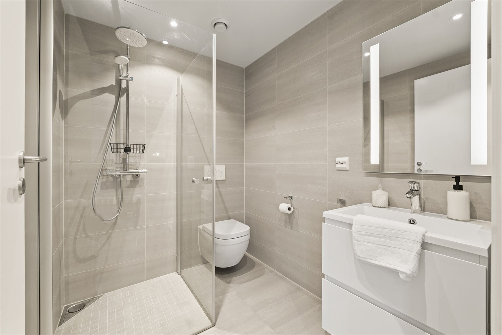 Moderne og lekkert baderom med gulvvarme i tilknytning til entréen, med et tidløst uttrykk som er innredet med stilrene materialvalg. Galleribilde