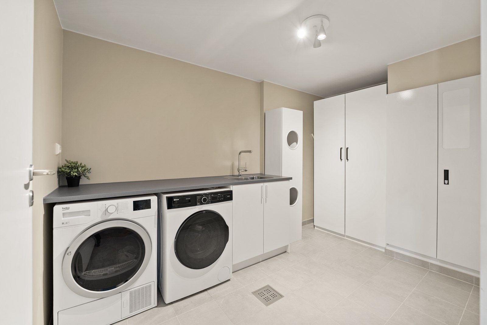 Praktisk vaskerom/teknisk rom med opplegg for vaskemaskin og tørketrommel. Her har man god benkeplass og lagringsmuligheter i skap. Galleribilde