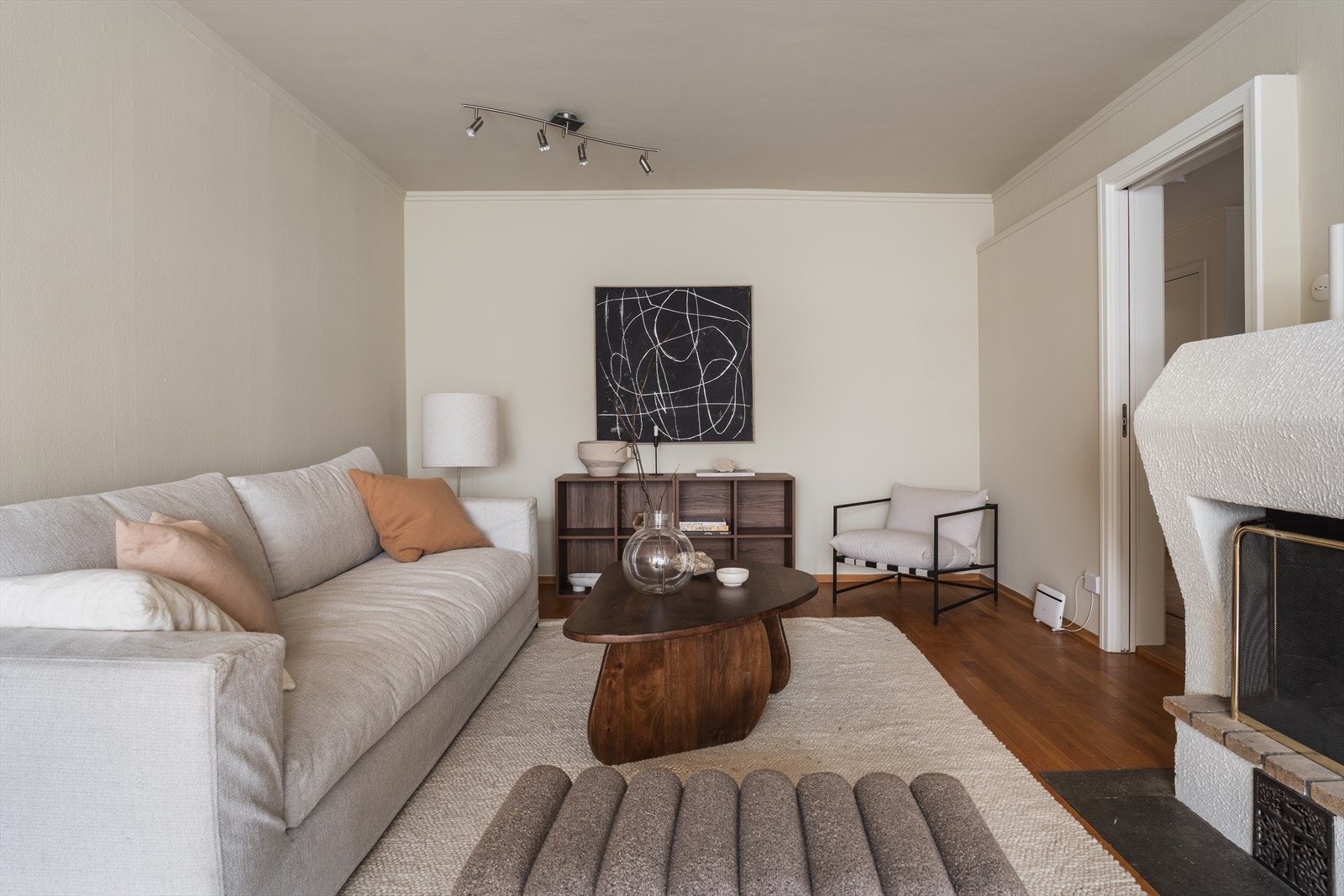 Stuen har plass til både sofa, lenestol og reol. Takskinne med spotter i taket. Galleribilde