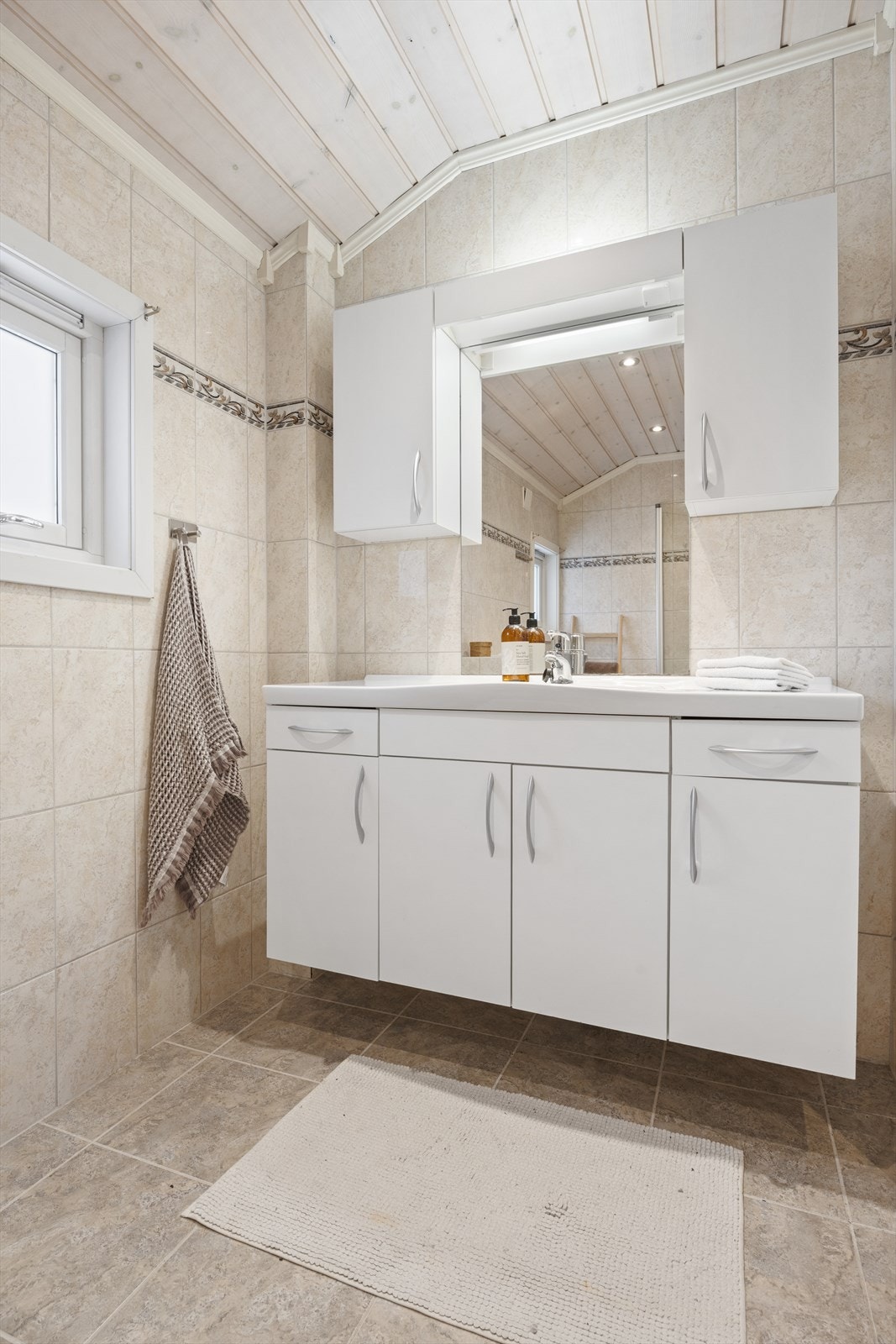 Badet er innredet med servantskap med nedfelt servant, veggskap med speil og belysning over og vegghengt klosett. Det er varme i gulvet. Deler av rommet er byggemeldt som kott. Galleribilde