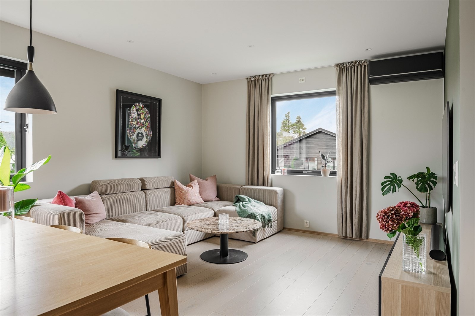 Oppholdsrommet har store vinduer mot to ulike himmelretninger som sørger for rikelig med naturlig lys. Alle vinduene i leiligheten har fine brede vinduskarmer som er perfekte for planter og dekor. Galleribilde