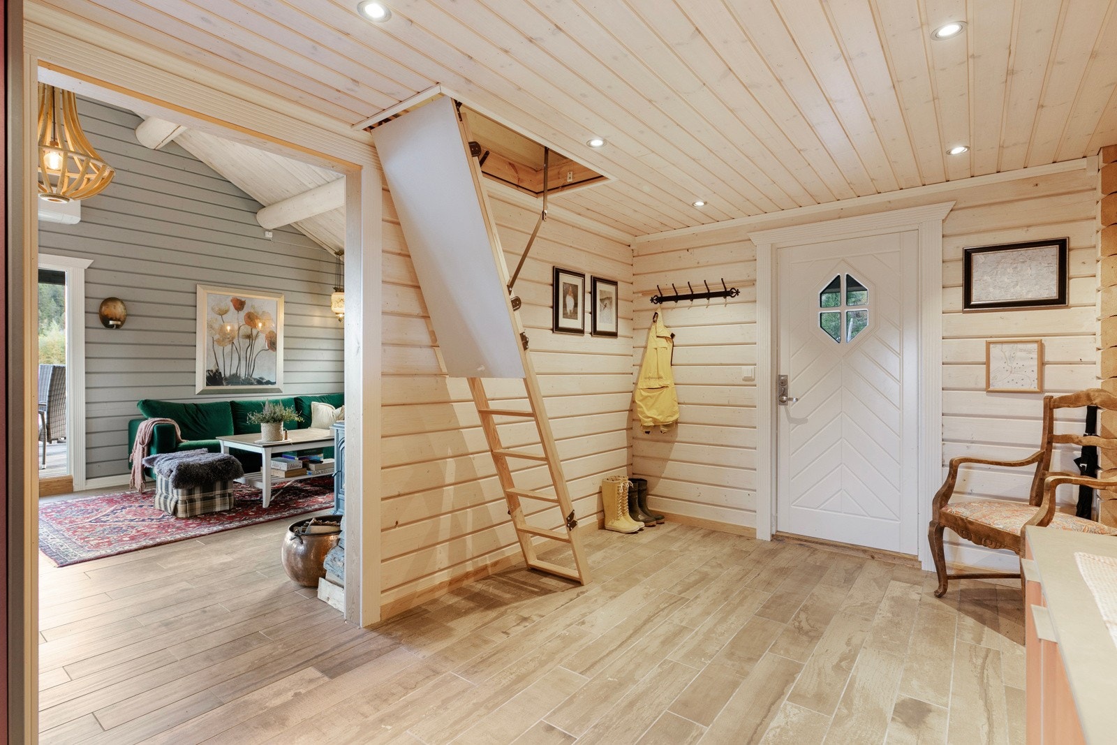 Lys og innbydende entre med vedlikeholdsfrie fliser på gulv med gulvvarme og panel og tømmer på vegger. Galleribilde