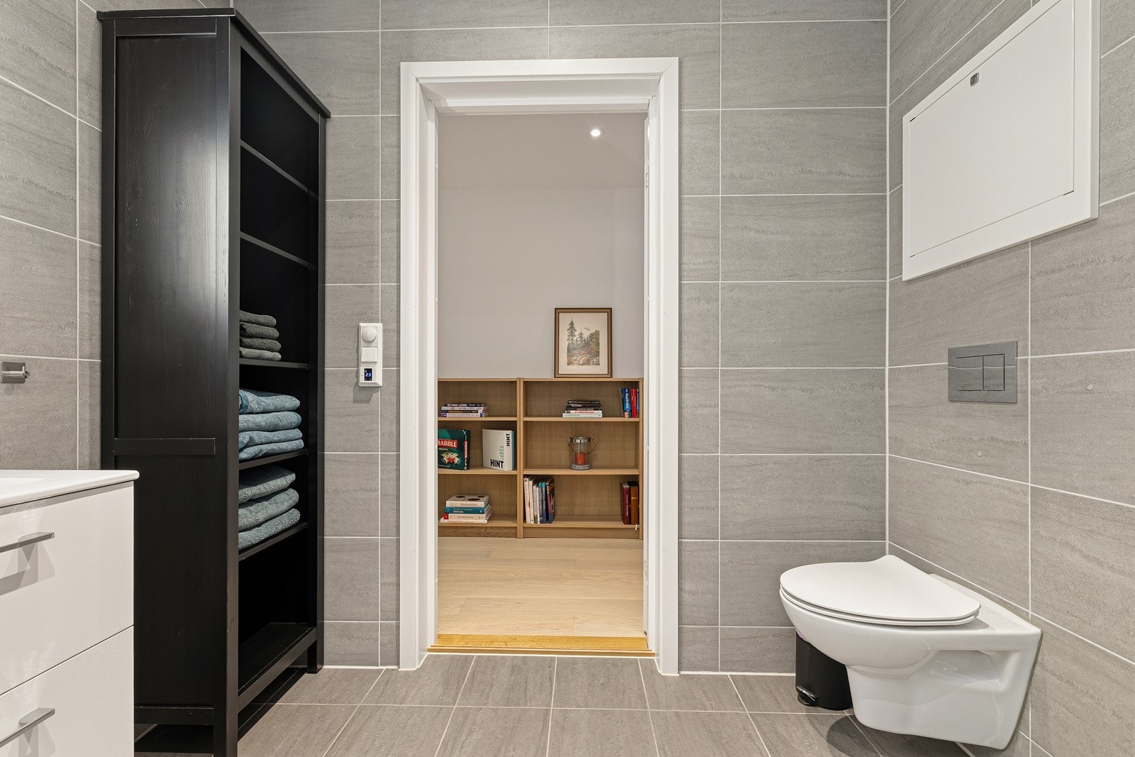 Baderomsinnredningen er lys med heldekkende nedfelt servant og rom for oppbevaring i skuffeseksjon og speil med belysning. Videre har badet dusjhjørne med innfellbare dusjvegger og vegghengt toalett. Badet har opplegg for vaskemaskin. Galleribilde