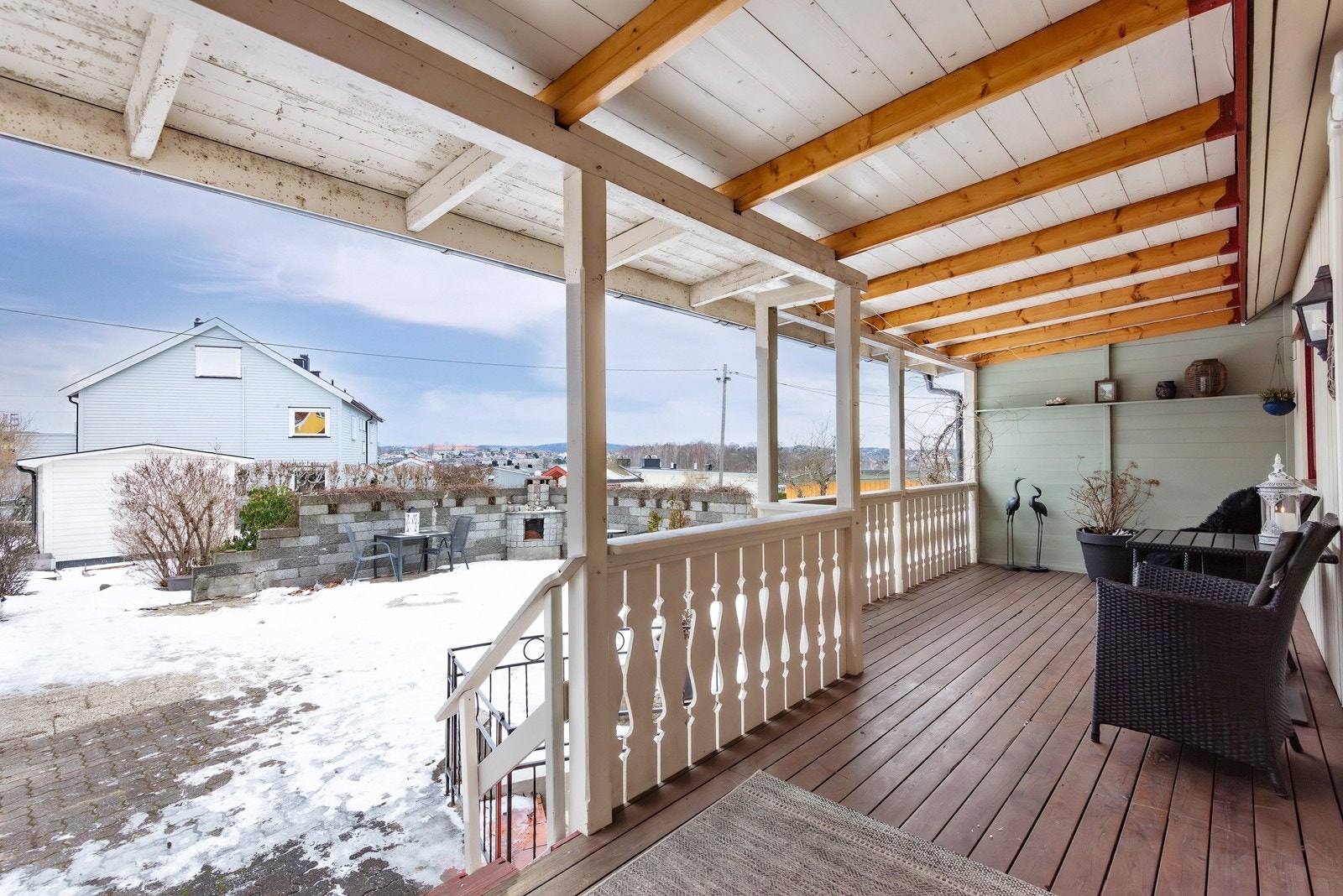 Inngangspartiet er tilbaketrukket på baksiden av boligen. Her ønskes du velkommen via en overbygget veranda som gir ly for vær og vind - et hyggelig ankomstområde som også egner seg godt som sitteplass i hverdagen. Galleribilde