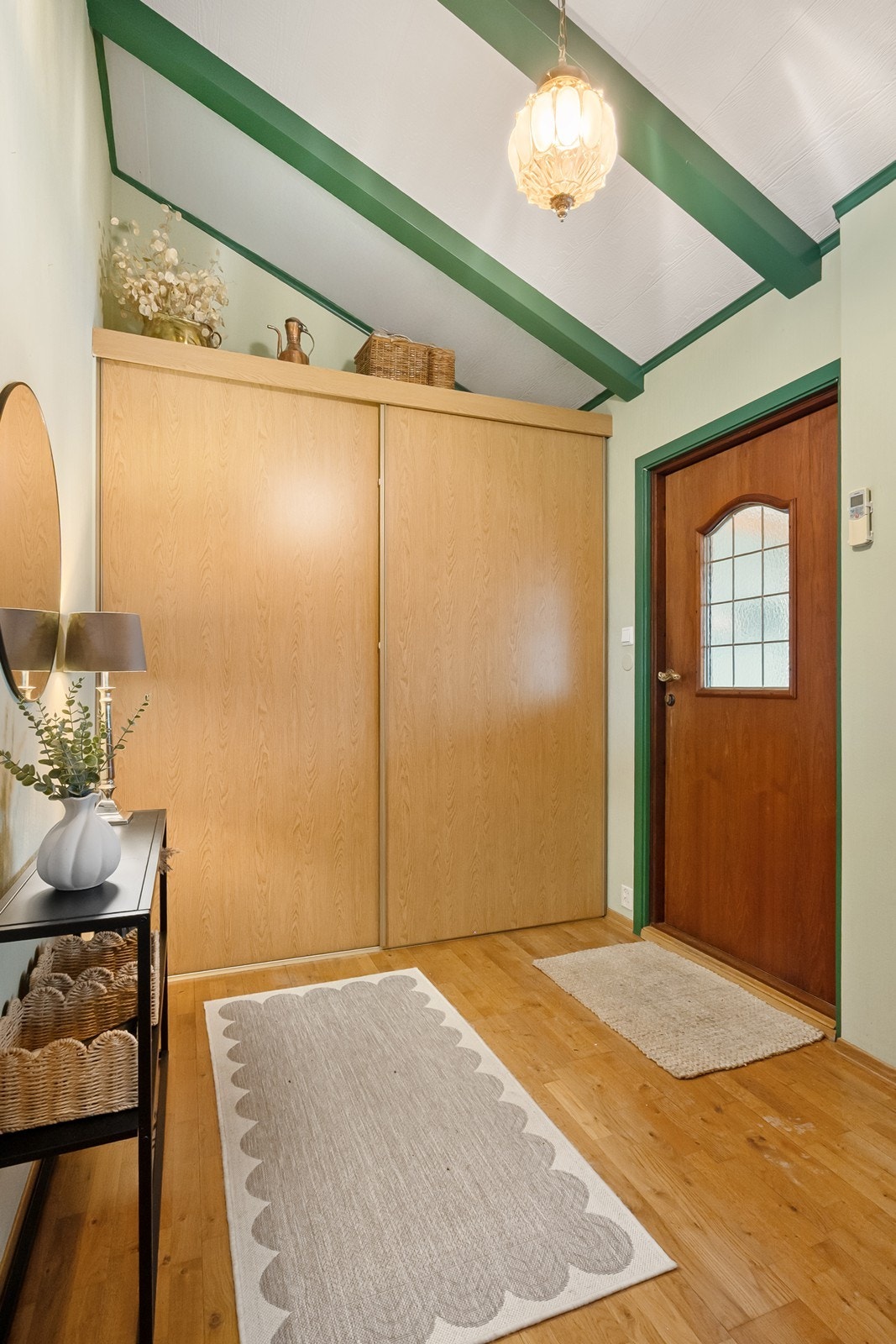 Inngangspartiet har god plass til oppbevaring i garderobeskap. Den gjennomgående bruken av treverk, detaljer i kontrastfarger og god takhøyde gir et varmt førsteinntrykk. Galleribilde