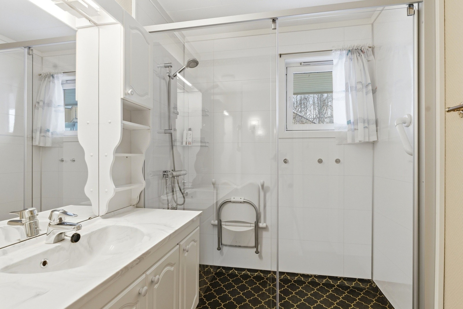 Lyst bad med innredning med tilhørende speil og dusj Galleribilde