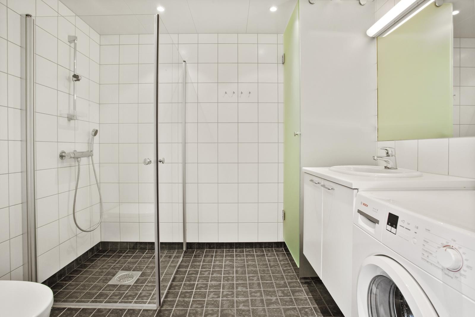 Flislagt bad med wc, servant, dusjhjørne, tørkeskap og vaskemaskin. Varmekabler i gulv. Galleribilde