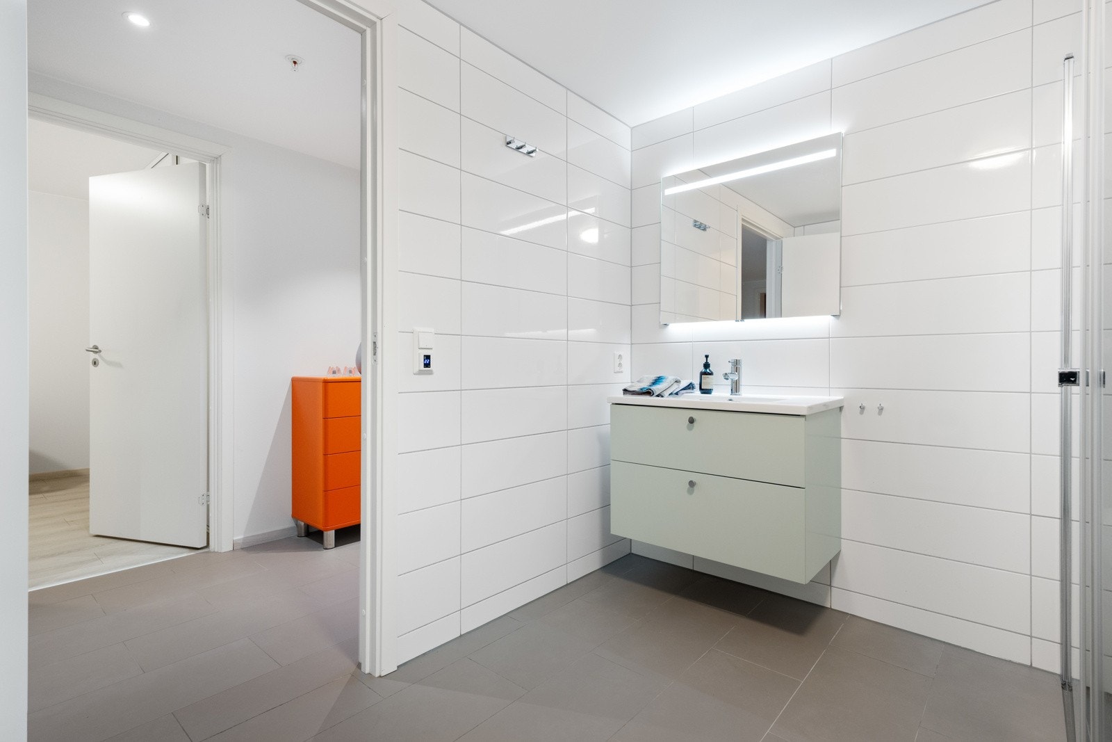 Badet har lekre baderomsmøbler med servant og speil med belysning. Nedsenket dusjsone med innskyvbare glassvegger. Vegghengt toalett og elektrisk håndkleholder med varme. Det er varme i gulv. Galleribilde