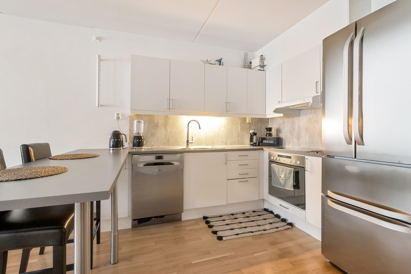 Kjøkkeninnredningen har hvite, glatte fronter og laminert benkeplate. Det er integrert stekeovn og platetopp i innredningen som medfølger. Galleribilde