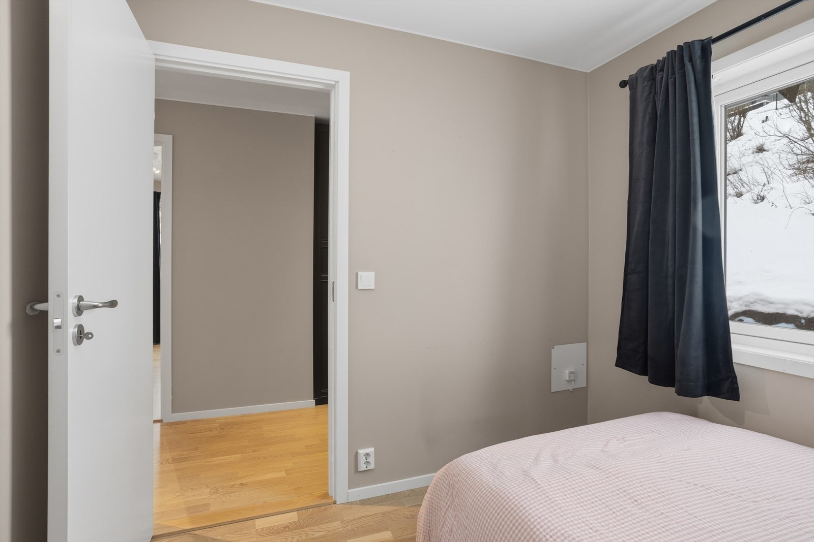 Lyst soverom med store vinduer som slipper inn naturlig lys og gir utsikt til snødekt landskap. Stilrent og moderne design. Galleribilde