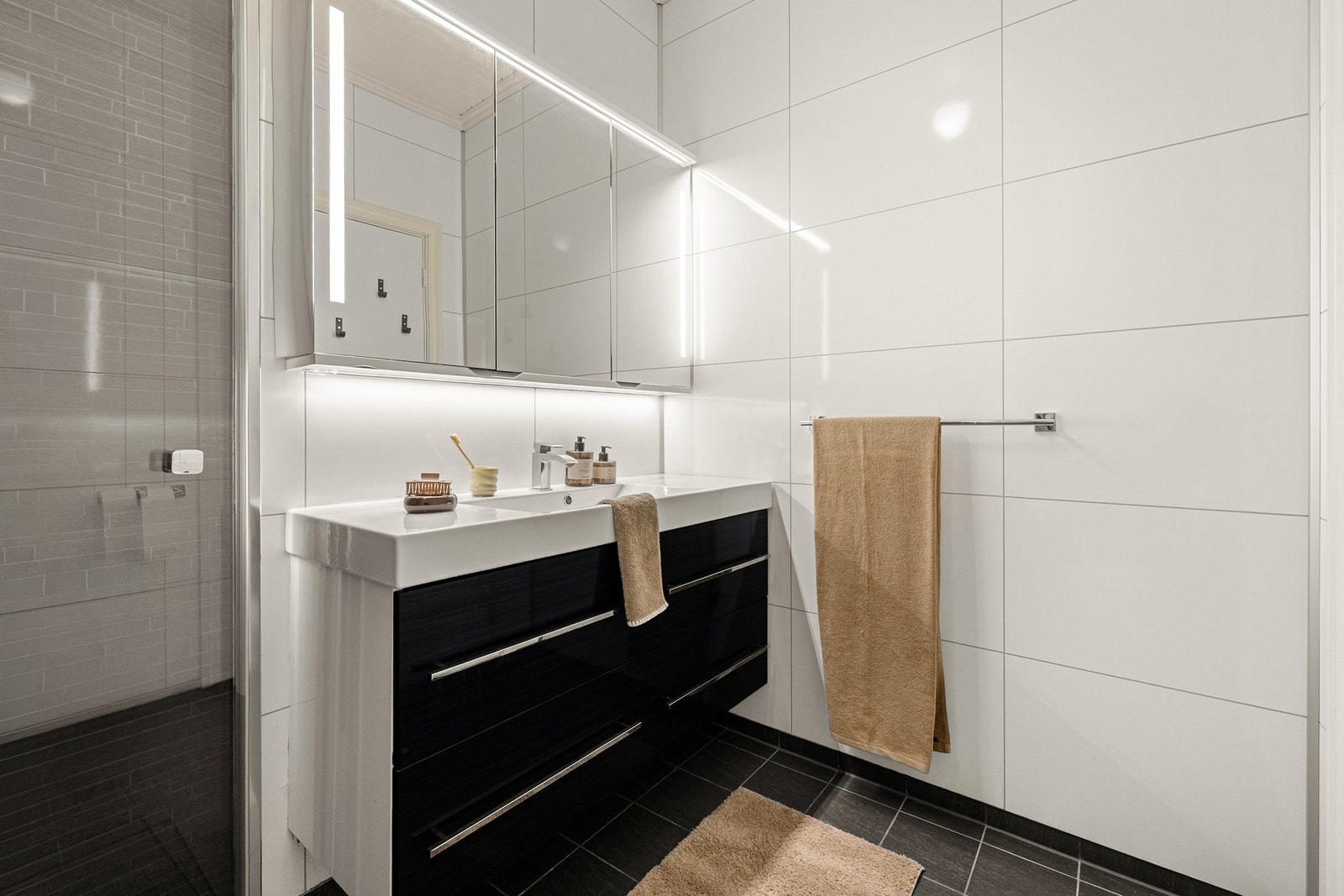 Det er varmekabler i gulv og er innredet med dusj med glassvegger, vegghengt toalett og baderomsinnredning. Galleribilde