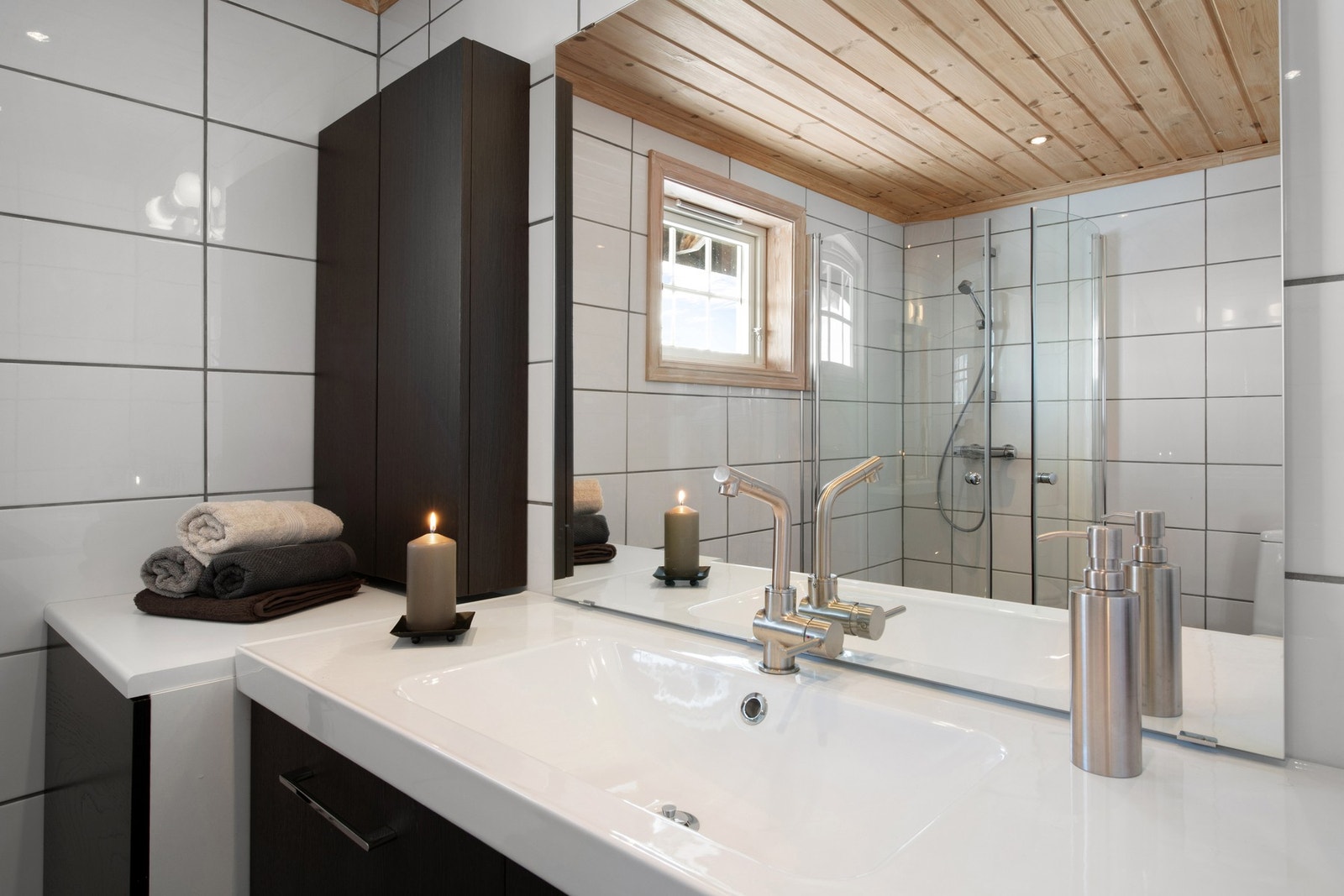 Badet består av servant og skapinnredning med mørke fronter, samt toalett og dusjhjørne med glassdører. Galleribilde