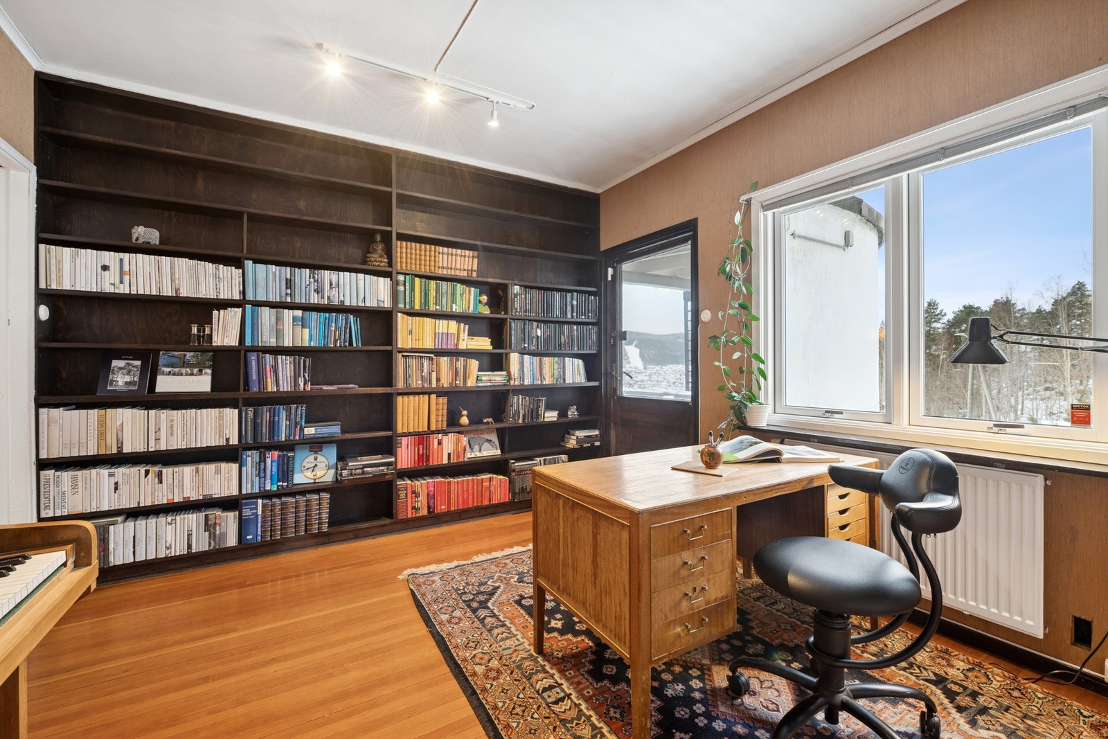 Stort bibliotek eller tv-stue med plassbygd bokhylle og utgang direkte til den flotte terrassen som har sol hele dagen. Galleribilde