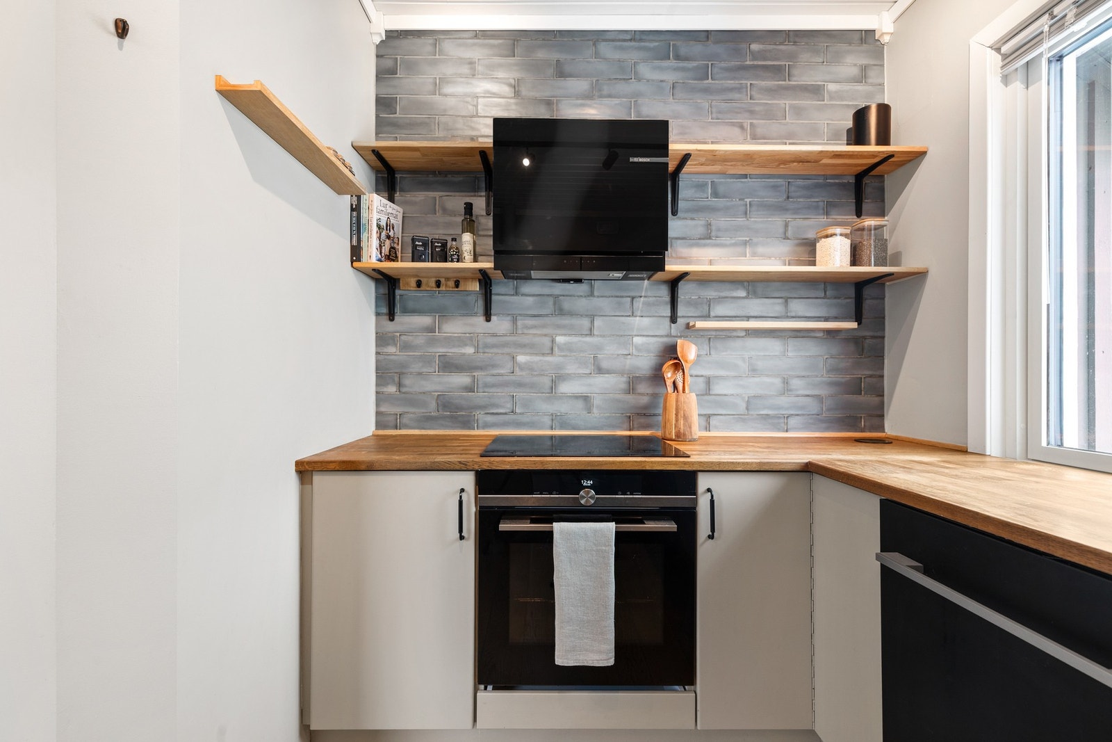 Innredningen har integrerte hvitevarer, herunder oppvaskmaskin, induksjonstopp og stekeovn Galleribilde