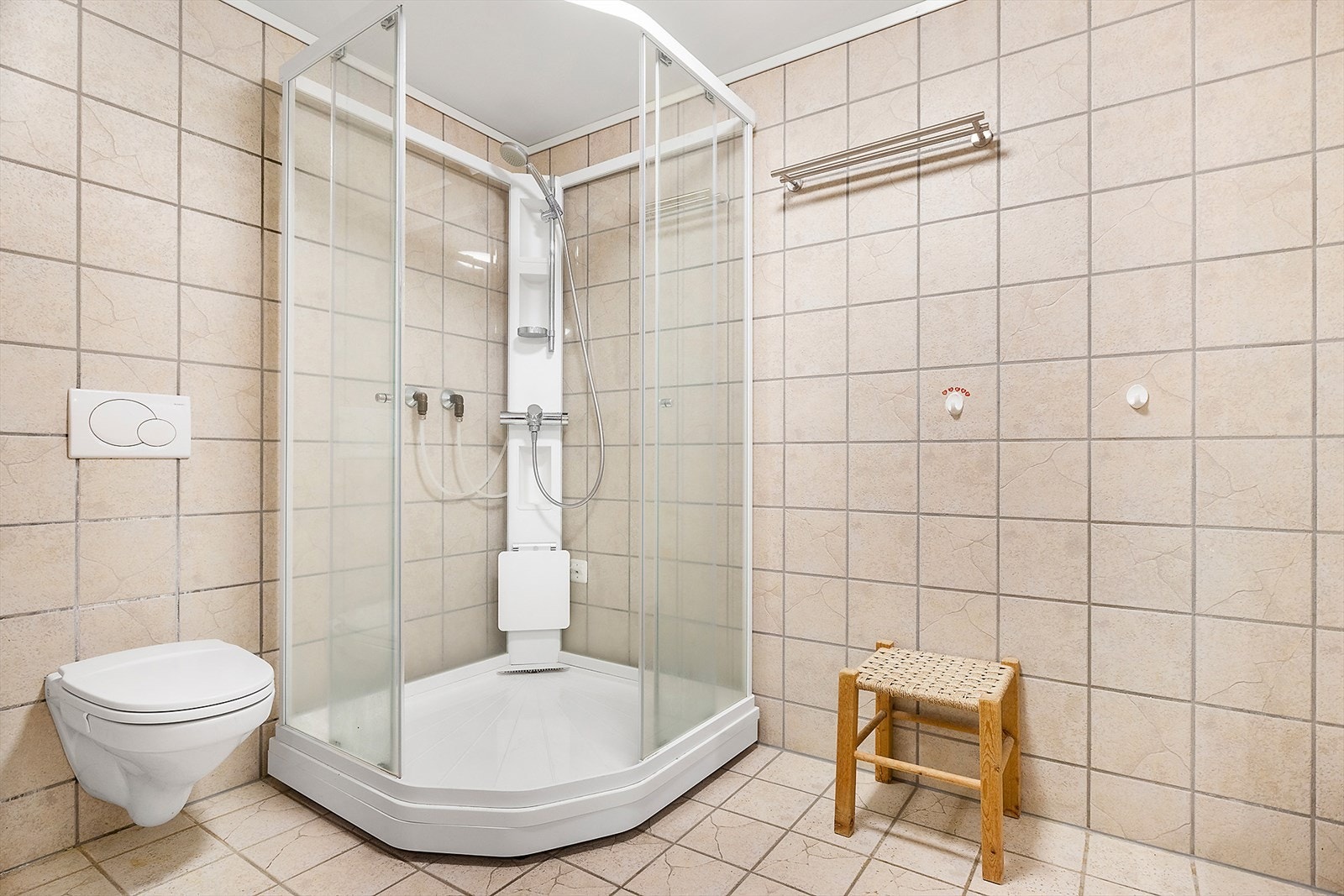 Flislagte gulv og vegger på badet som har vegghengt toalett og dusjkabinett Galleribilde