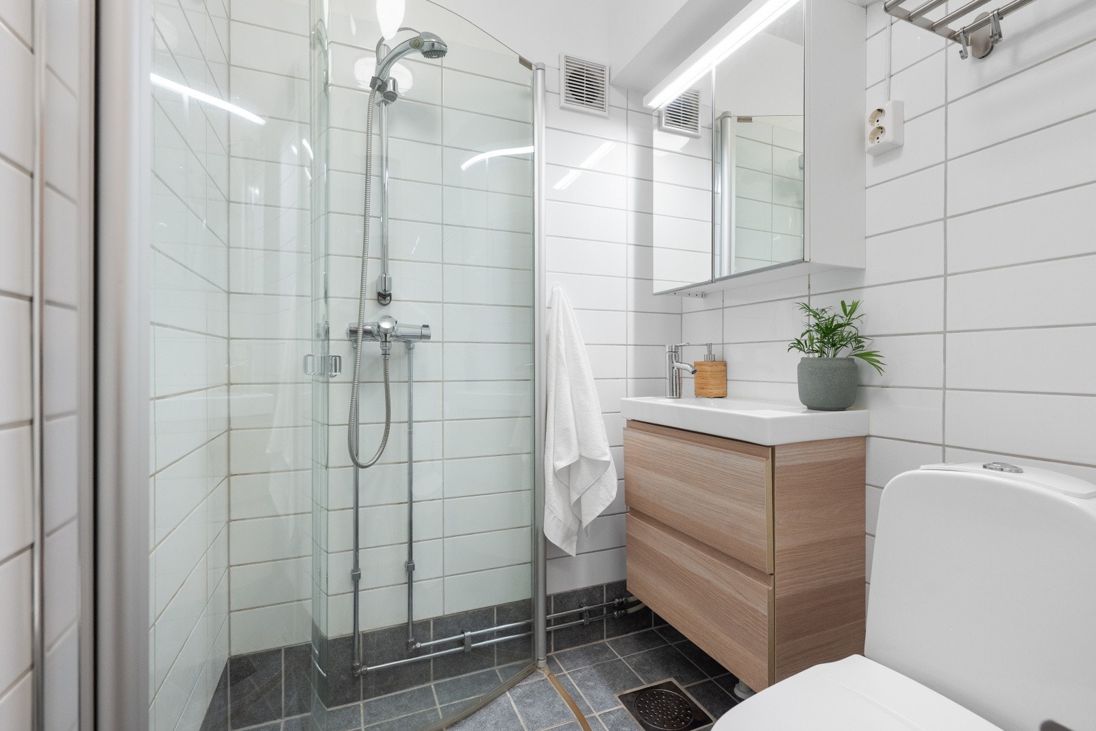 Badet er innredet med nedfelt servant og glatte fronter, veggskap med speilfronter, toalett og dusj på gulv. Det er varmekabler i gulvet. Galleribilde